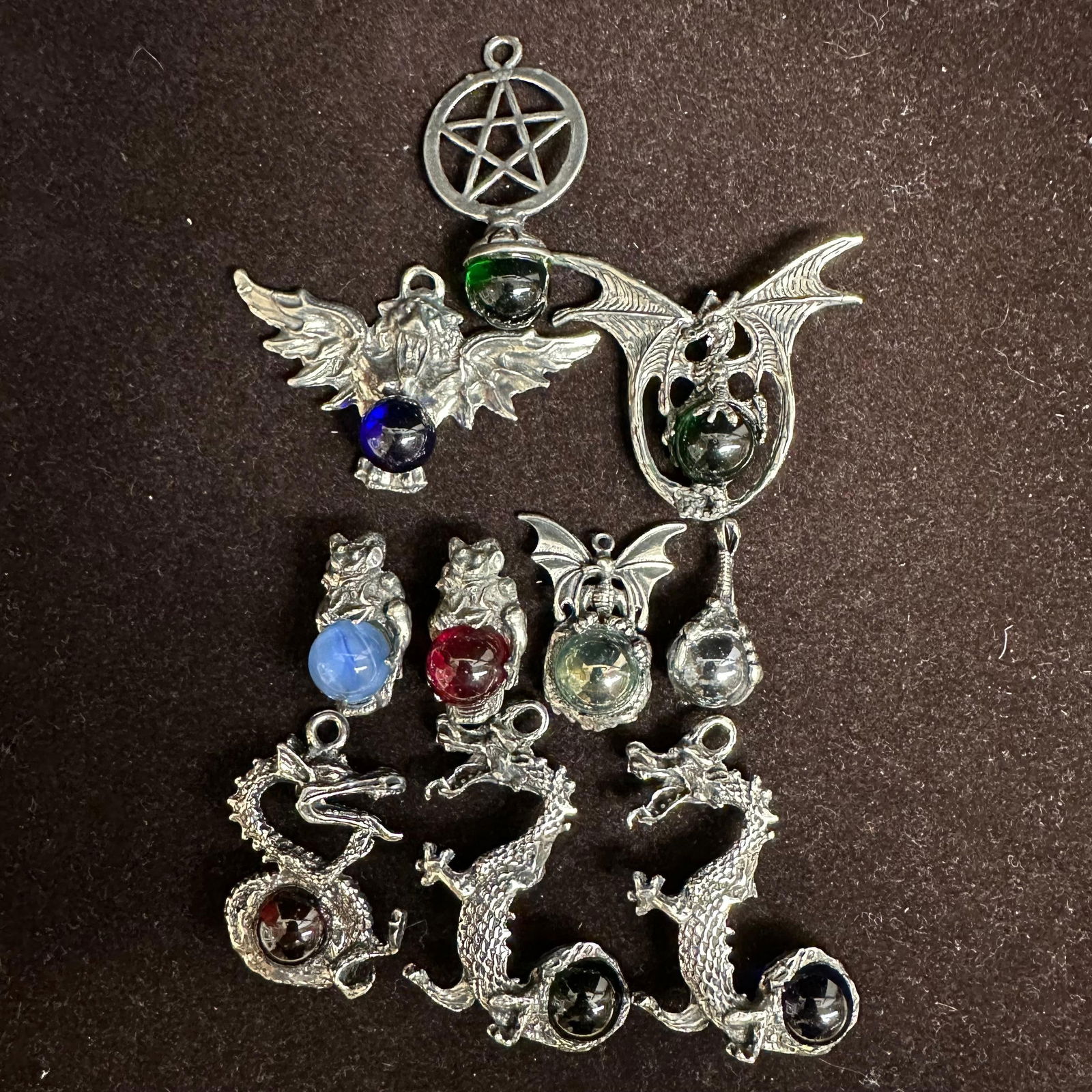 Fantasy Dragon Gargoyle and Pentagram Metal Pendants with Colored Orbs Marbles Ten Pieces: Group of ten vintage fantasy-style metal pendants, each featuring cast dragon, gargoyle, bat-wing, or pentagram motifs set with colored glass or acrylic orbs. Various forms include standing gargoyles