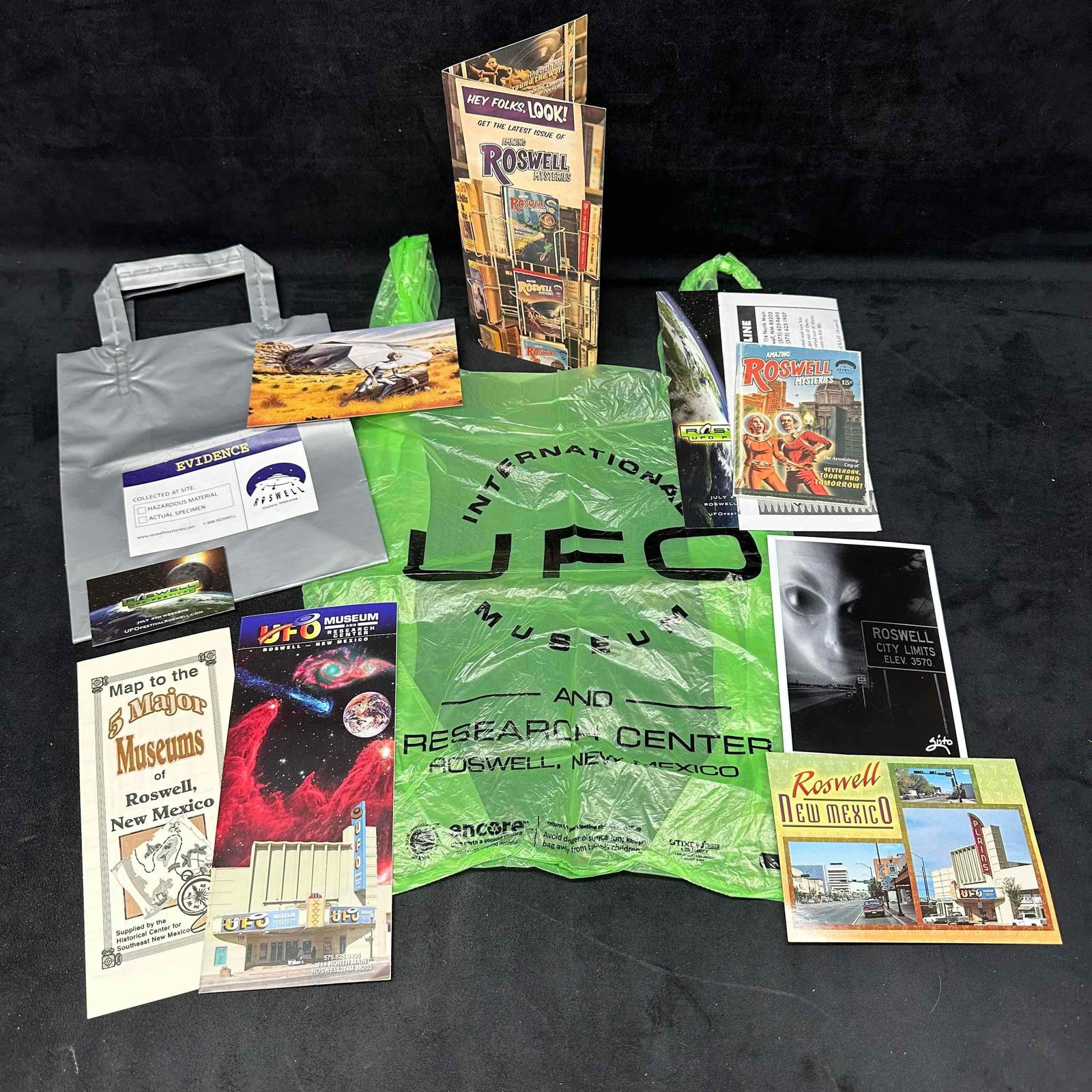 Lot of Roswell UFO Museum and Souvenir Ephemera Memorabilia: Collection of Roswell, New Mexico UFO-themed memorabilia including brochures, postcards, souvenir bags, and ephemera from the International UFO Museum and surrounding attractions. Items include museum
