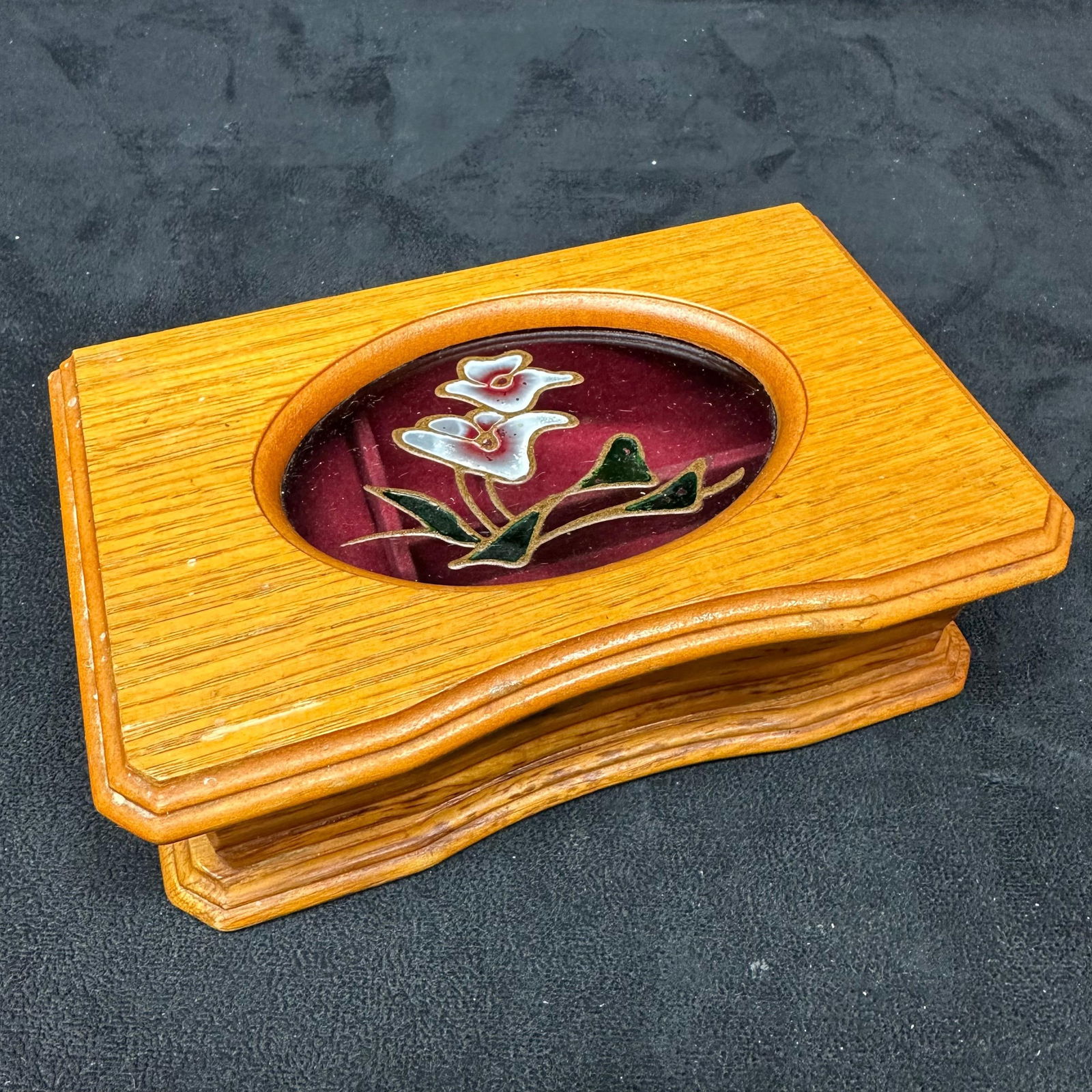 Vintage Mele Wooden Jewelry Box with Cloisonne Floral Inlay: Vintage jewelry box by Mele, crafted in wood with a glass oval inset featuring cloisonne-style floral decoration. The interior is lined in red velvet with ring slots and open compartments. Retains the
