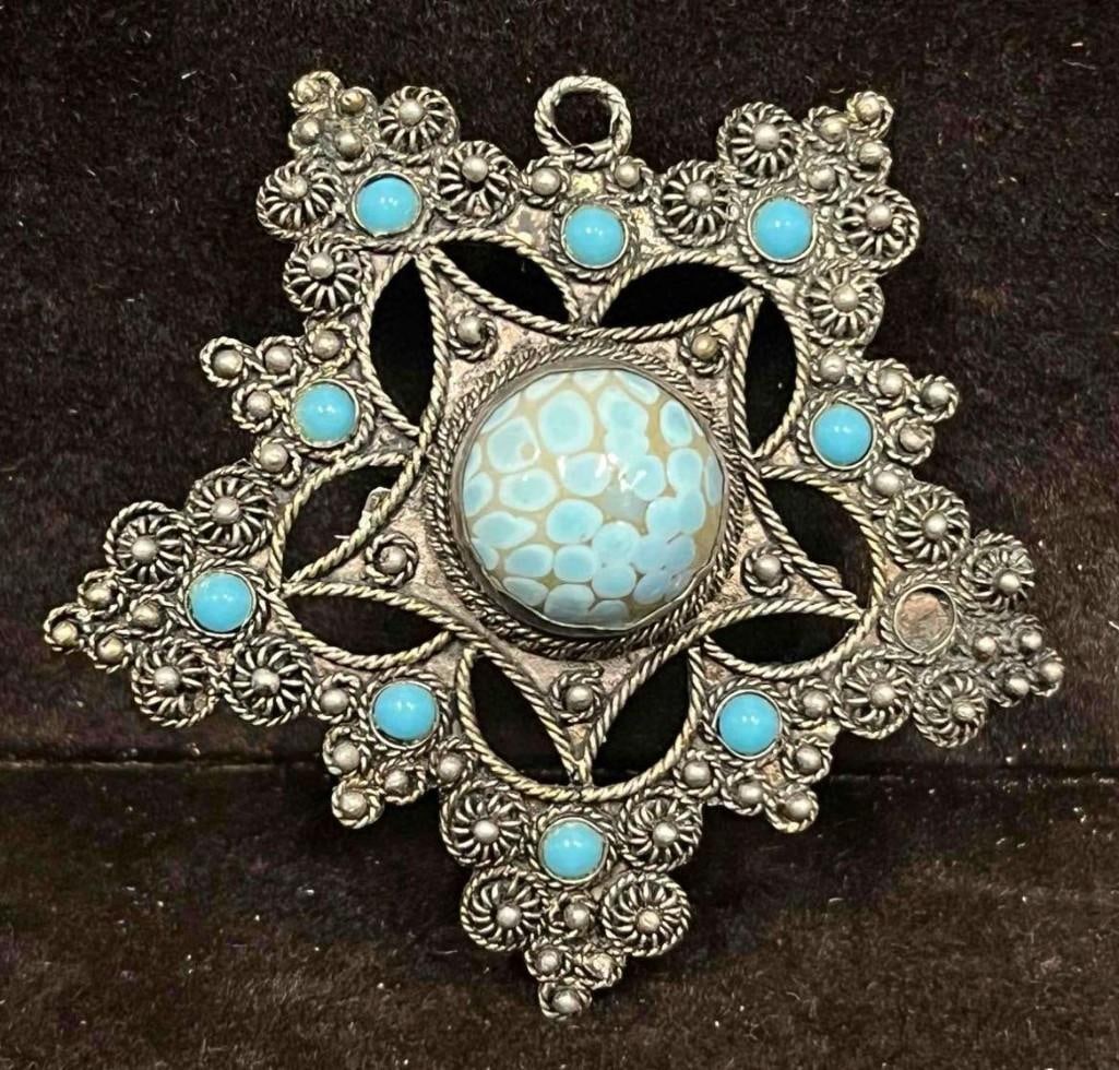 Unique Intricate Silver Tone Pendant/Brooch With Blue Stones: This lot contains a Unique Intricate Silver Tone Pendant/Brooch With Blue Stones. The brooch is approx 2 1/4" x 2 1/4" x 1/2". Total weight is approx 0.4oz. Overall the brooch is in good pre owned con