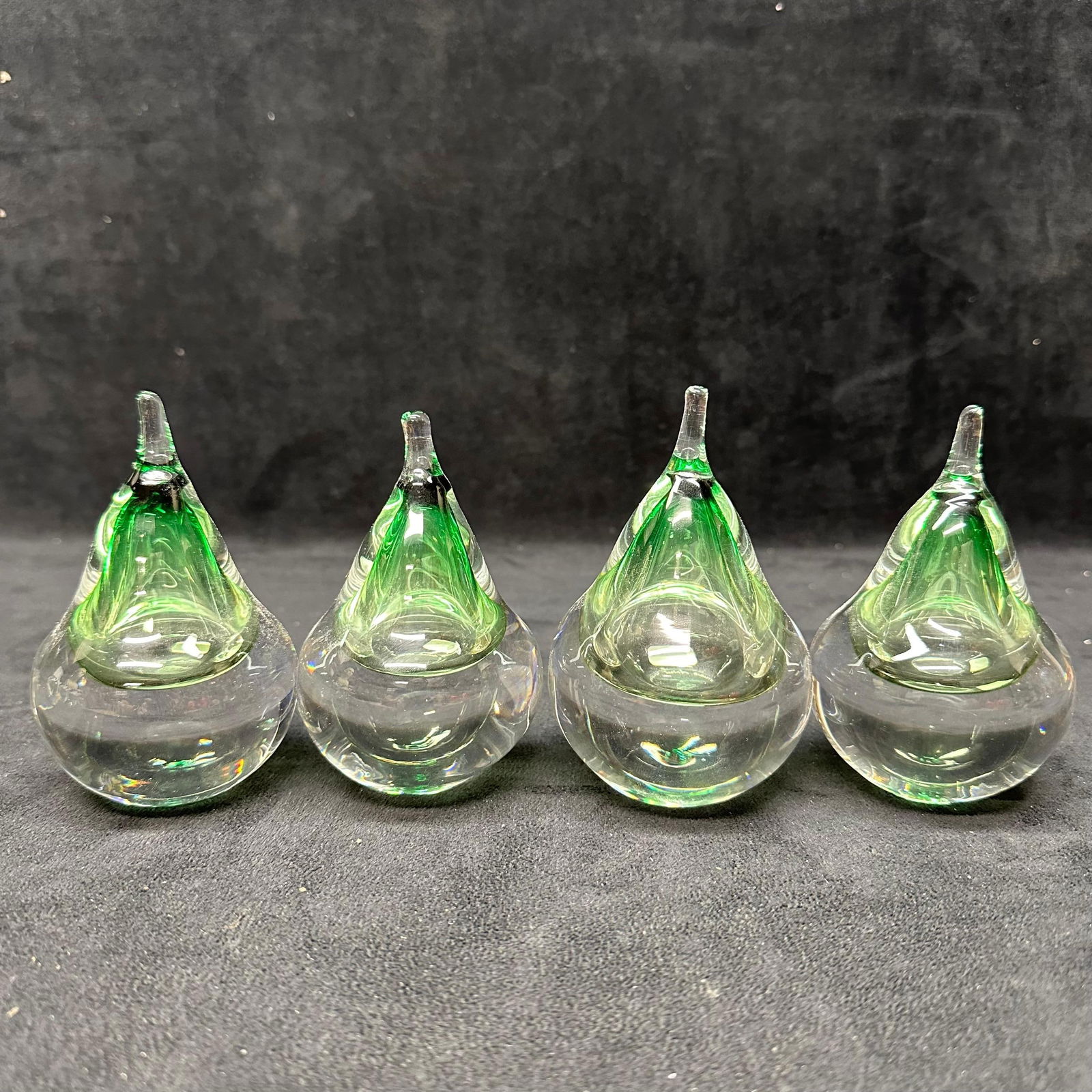 Studio Ahus Sweden Art Glass Green Teardrop Paperweights Set of Four Pear Shaped: Set of four Studio Ahus art glass paperweights featuring clear bodies with internal green teardrop forms. Each piece is signed and retains the original Studio Ahus Sweden label on the base. Hand-blown