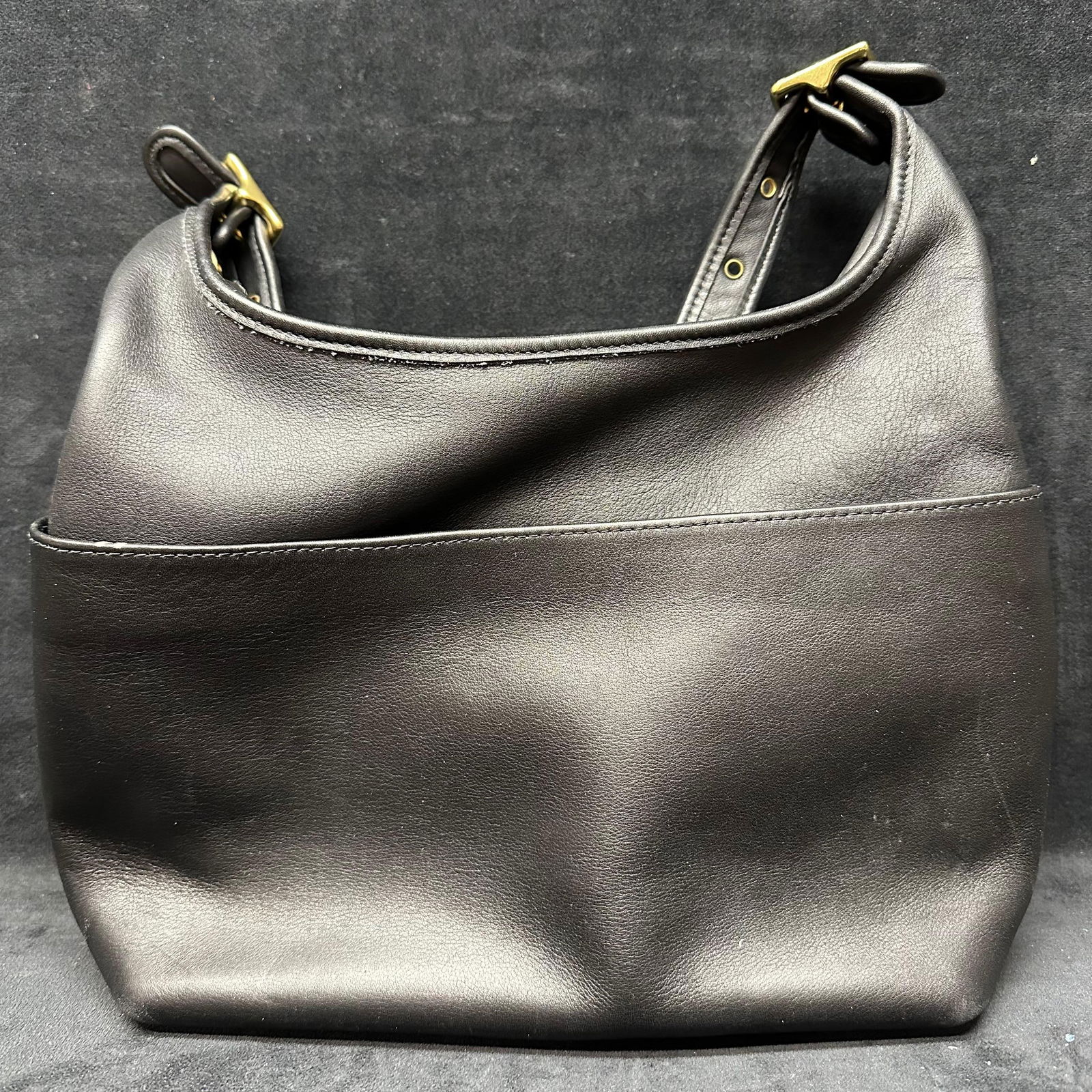 Coach Black Leather Hobo Shoulder Bag: Coach black leather hobo-style shoulder bag with adjustable strap and brass-tone hardware. Soft pebbled leather exterior with structured base. Zip-top closure opening to a fabric-lined interior with a