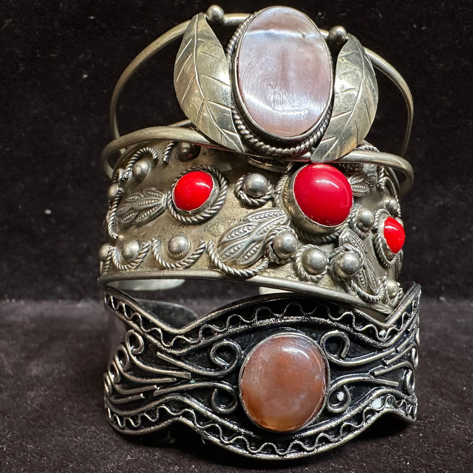 Group of Three Vintage Alpaca and Base Metal Costume Jewelry Cuff Bracelets: The lot includes three vintage costume jewelry cuff bracelets. One marked Mexico Alpaca with a pink cabochon and leaf detail; one marked Made in Italy ALP with red cabochon accents; and one unmarked o