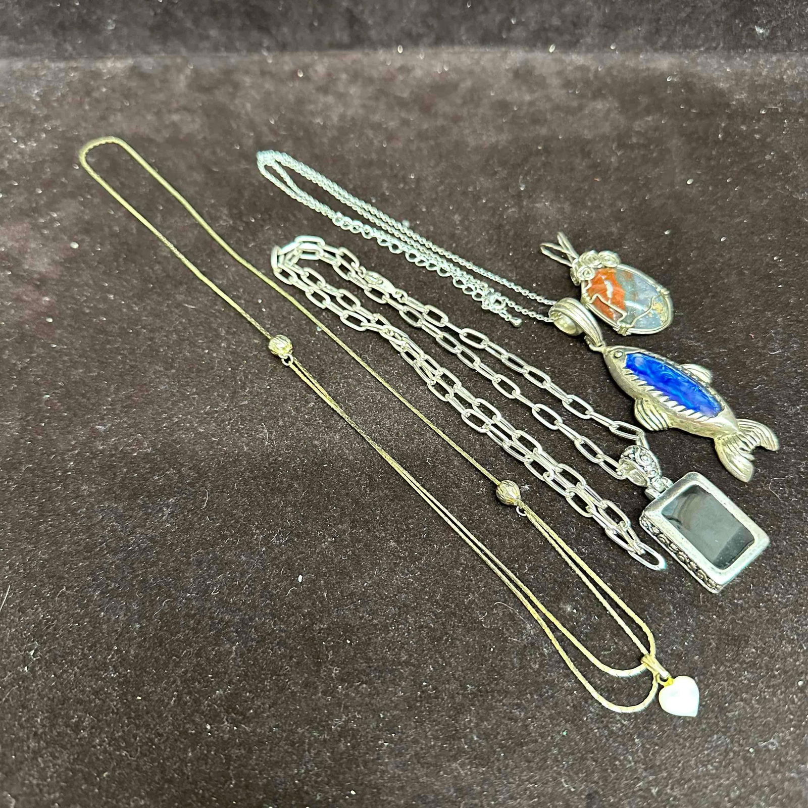 Costume Jewelry Set Pendant Necklaces with Natural Stone and Mother of Pearl K25: Collection of four costume necklaces with silver and gold plated chains. Includes a heart pendant with mother of pearl, a rectangular pendant with dark stone, a large fish pendant with blue stone, and