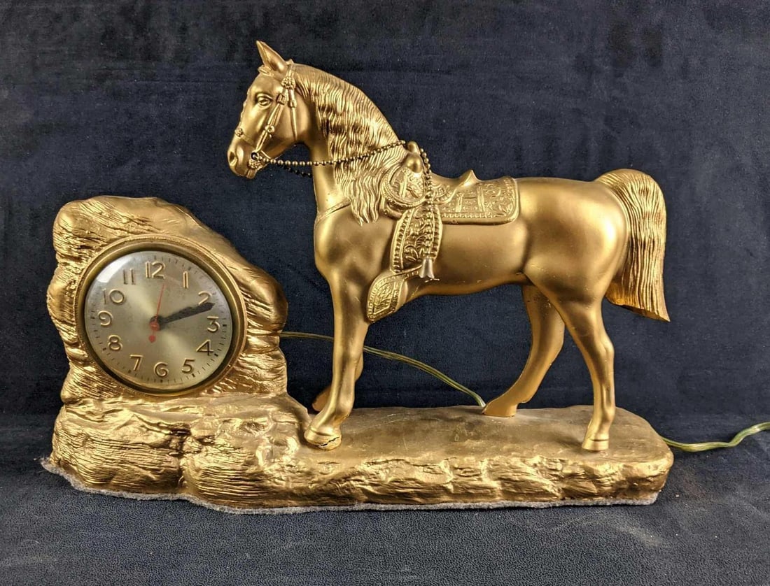 Gold Colored Horse Statue Clock: Gold Colored Horse Statue Clock This is a ceramic gold-painted horse next to a rock where a clock is located. This statue has a crack in its hoof and the clock has not been tested. This is a beautiful