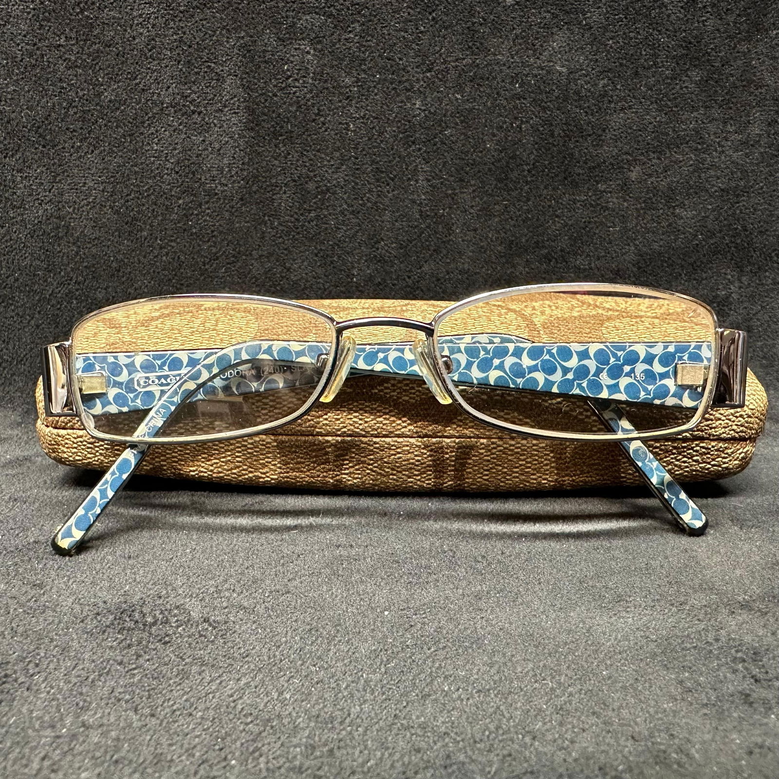 Coach Teodora 240 Slate Eyeglasses with Case: Coach Teodora model 240 eyeglasses in the Slate colorway. Rectangular metal frames with patterned blue Coach logo temples. The interior arm is marked Coach Teodora 240 Slate. Includes original Coach c