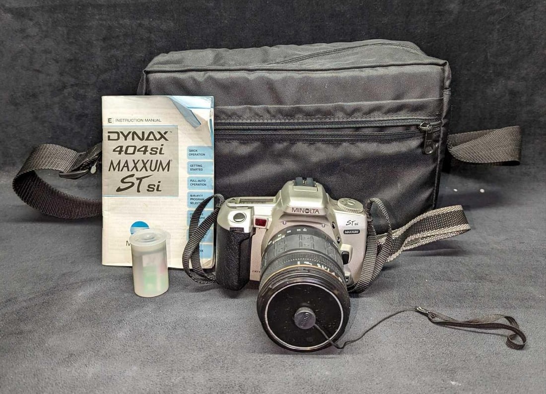 Minolta Dynax 404si Maxxum Camera & Case & Lens: Minolta Dynax 404si Maxxum Camera & Case & Lens. Comes with camera, one roll of 35mm film, an instruction manual, and a 28-200mm Aspherical IF Lens. Comes in a bag (is not marked or tagged by any comp