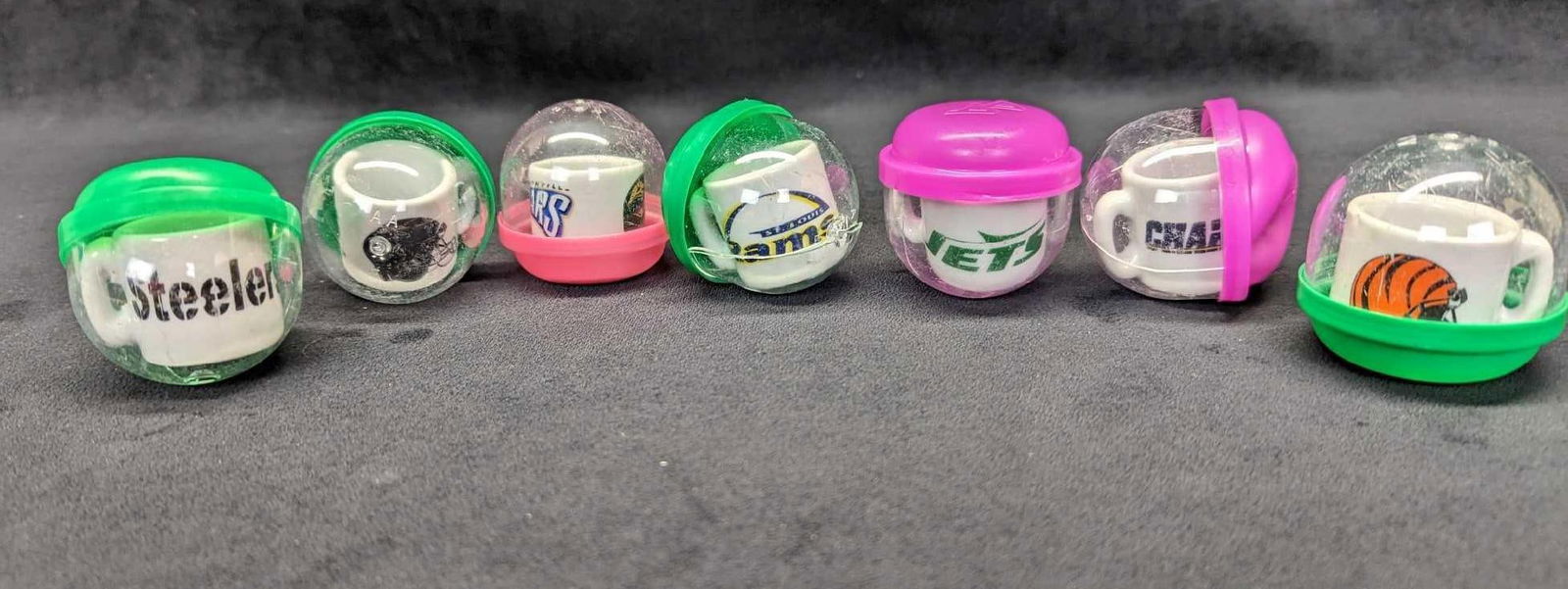 7 Mini Ceramic NFL Football Team Mugs: 7 Mini Ceramic NFL Football Team Mugs. Here are seven little capsule toys. Each is still in its original capsule. The capsules are approx 1 3/4" x 1 3/4" x 2". The mugs inside are approx