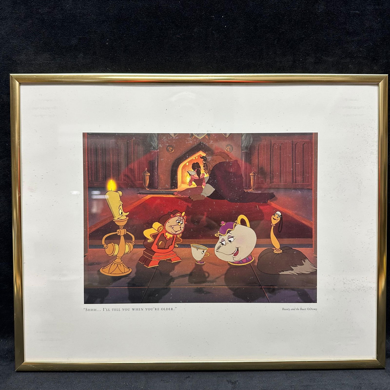 Beauty and the Beast I'll Tell You When You're Older Gold Frame Disney Lithograph: "Shhh...I'll Tell You When You're Older" Beauty and the Beast Disney lithograph framed in a gold-toned hard plastic. Minor water spots and stains are noticed on the glass. This item is
