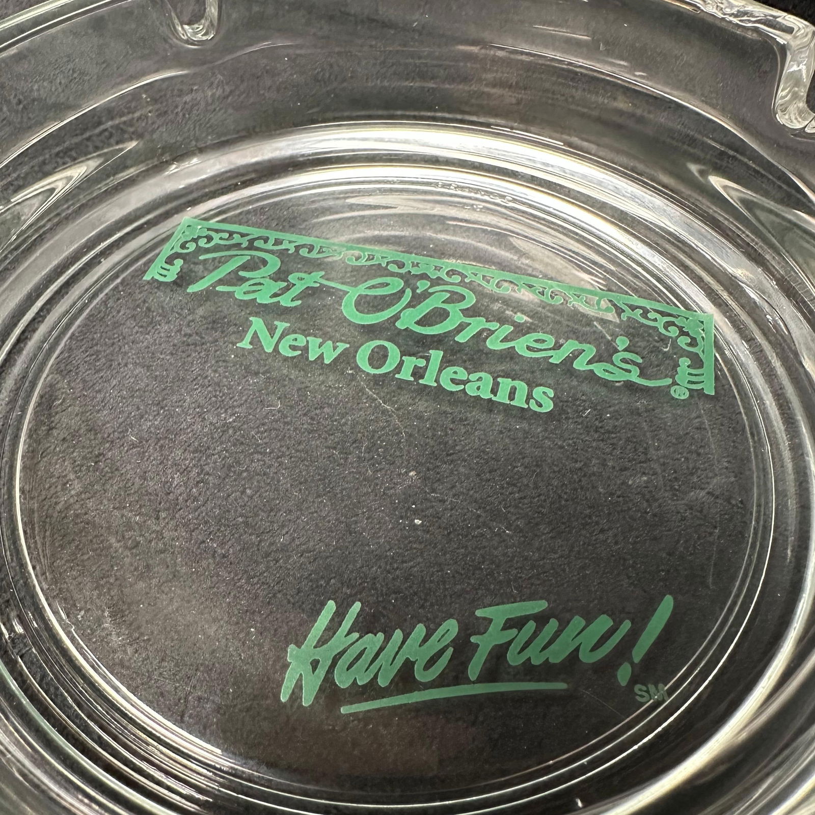 Pat O’Brien’s New Orleans Glass Ashtray Have Fun France: Clear glass Pat O’Brien’s New Orleans souvenir ashtray featuring the bar’s iconic green logo and “Have Fun!” slogan. Marked France on the rim. Minor production error on the rim, looks li