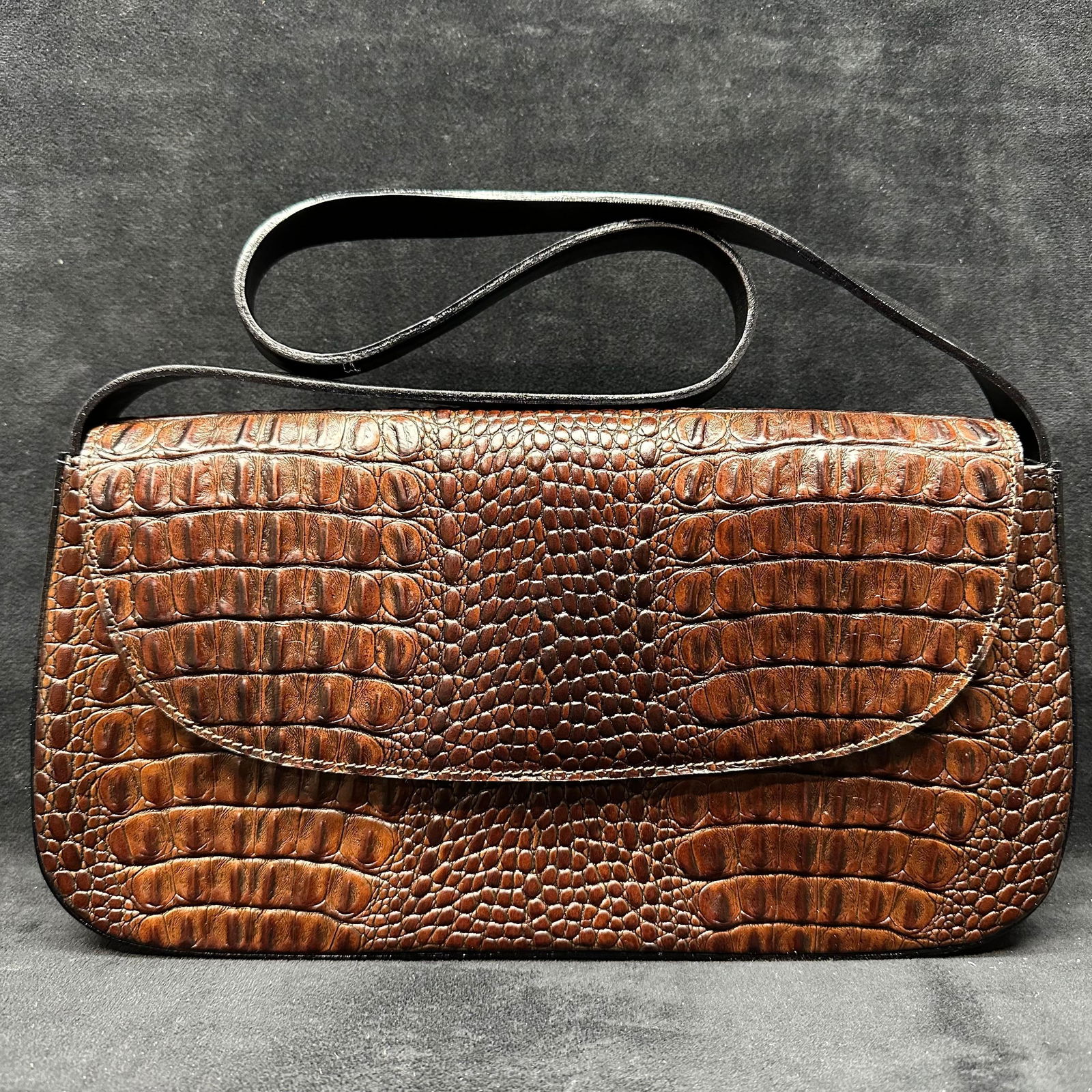 Brahmin Brown Crocodile Embossed Leather Clutch Shoulder Bag: Brahmin leather clutch crafted in brown crocodile-embossed leather. Features a flap front with snap closure, structured rectangular form, and black leather interior stamped BRAHMIN. Interior offers a