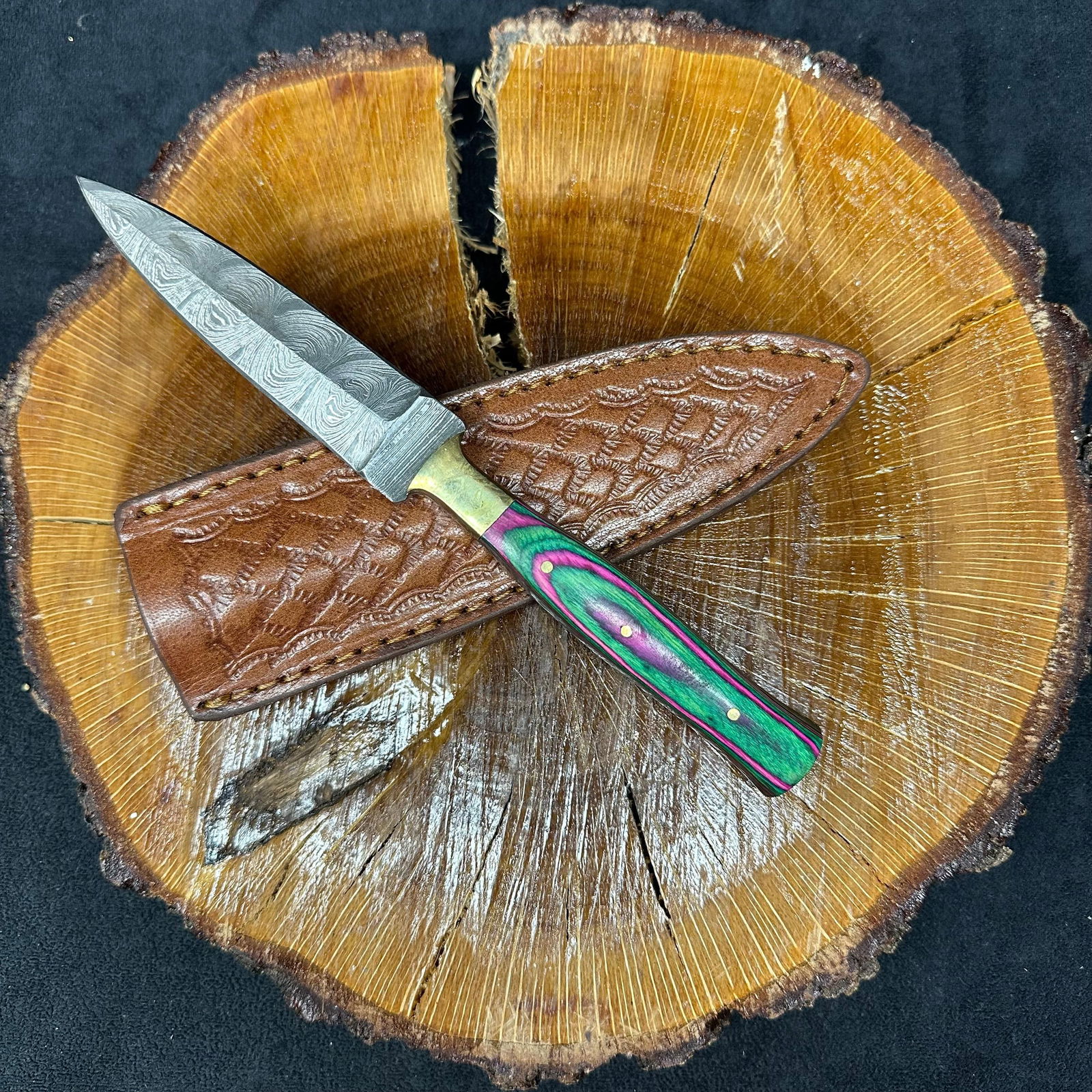Fixed Blade Knife Spear Point Dagger Style MHS Cutlery Q22 Pink Green: Fixed dagger-style blade knife by MHS Cutlery featuring a layered patterned steel blade and decorative spine work. The handle has a contoured, multi-colored wood/epoxy resin-style grip with metal mosa