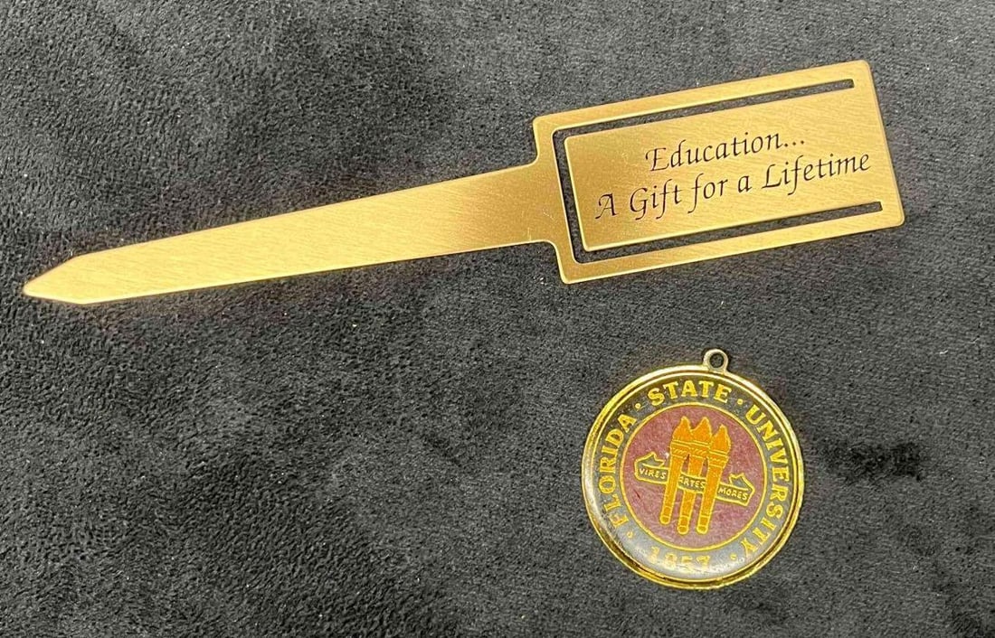 FSU Education Small Bundle Pendant & Book Mark: This lot contains a FSU Education Small Bundle Pendant & Book Mark. The book mark is approx 6 3/4" x 1 1/4" and the pendant is approx 1 3/4" x 1 3/4". Total weight is approx 1.2oz. Overall the