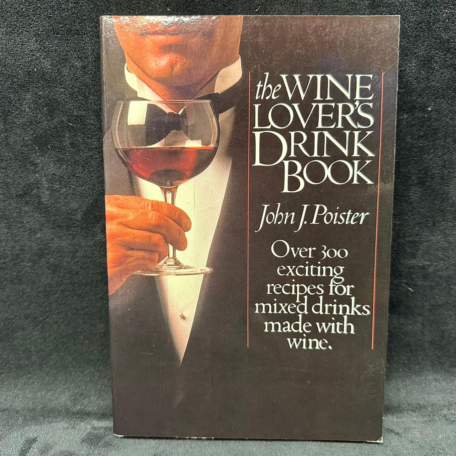 The Wine Lover's Drink Book Signed by John J. Poister Softcover: Signed by John J. Poister with a personal inscription dated 1997 to Michel Roux. Condition shows general handling wear, scuffing, and surface marks to the cover consistent with age. Interior pages