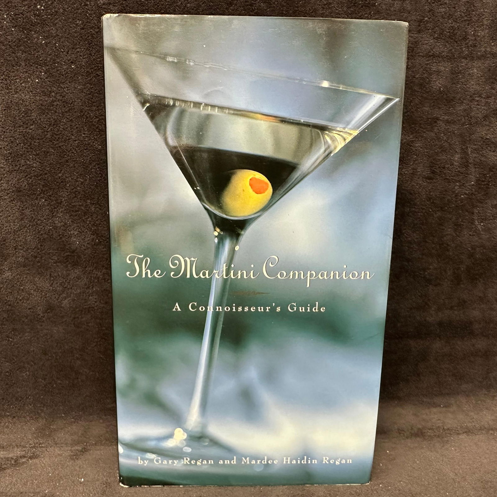 The Martini Companion A Connoisseur's Guide Signed Hardcover Book: Signed by Gary Gegan and Mardee Haiden Regan with a personal inscription to Michel Roux. Condition shows general handling wear, scuffing, and surface marks to the cover consistent with age. Interior