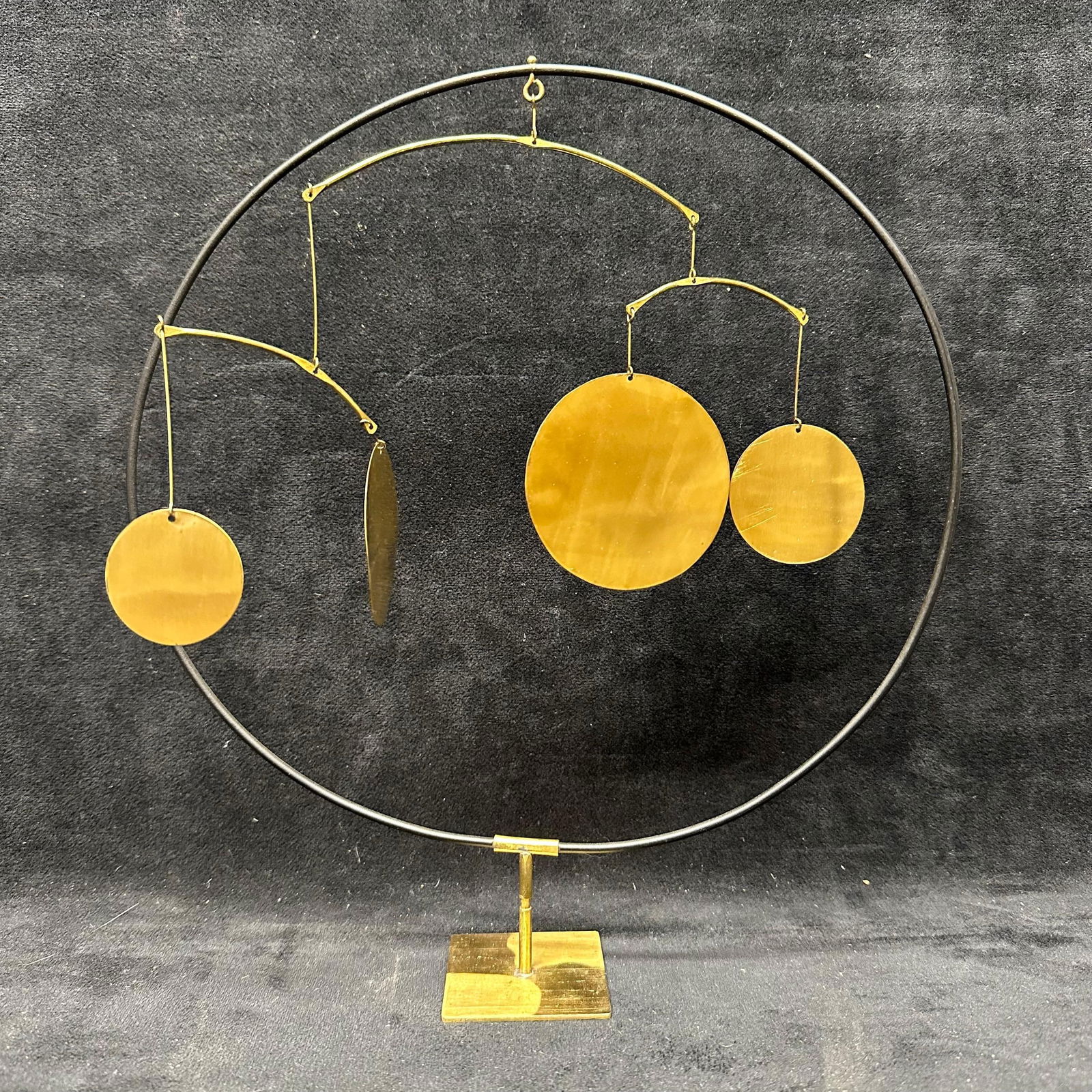 Decorative Kinetic Balance Sculpture with Brass Discs on Stand: Decorative tabletop kinetic balance sculpture featuring suspended circular and oval brass-toned discs arranged on curved metal arms within a circular frame. Mounted on a weighted rectangular base. Des