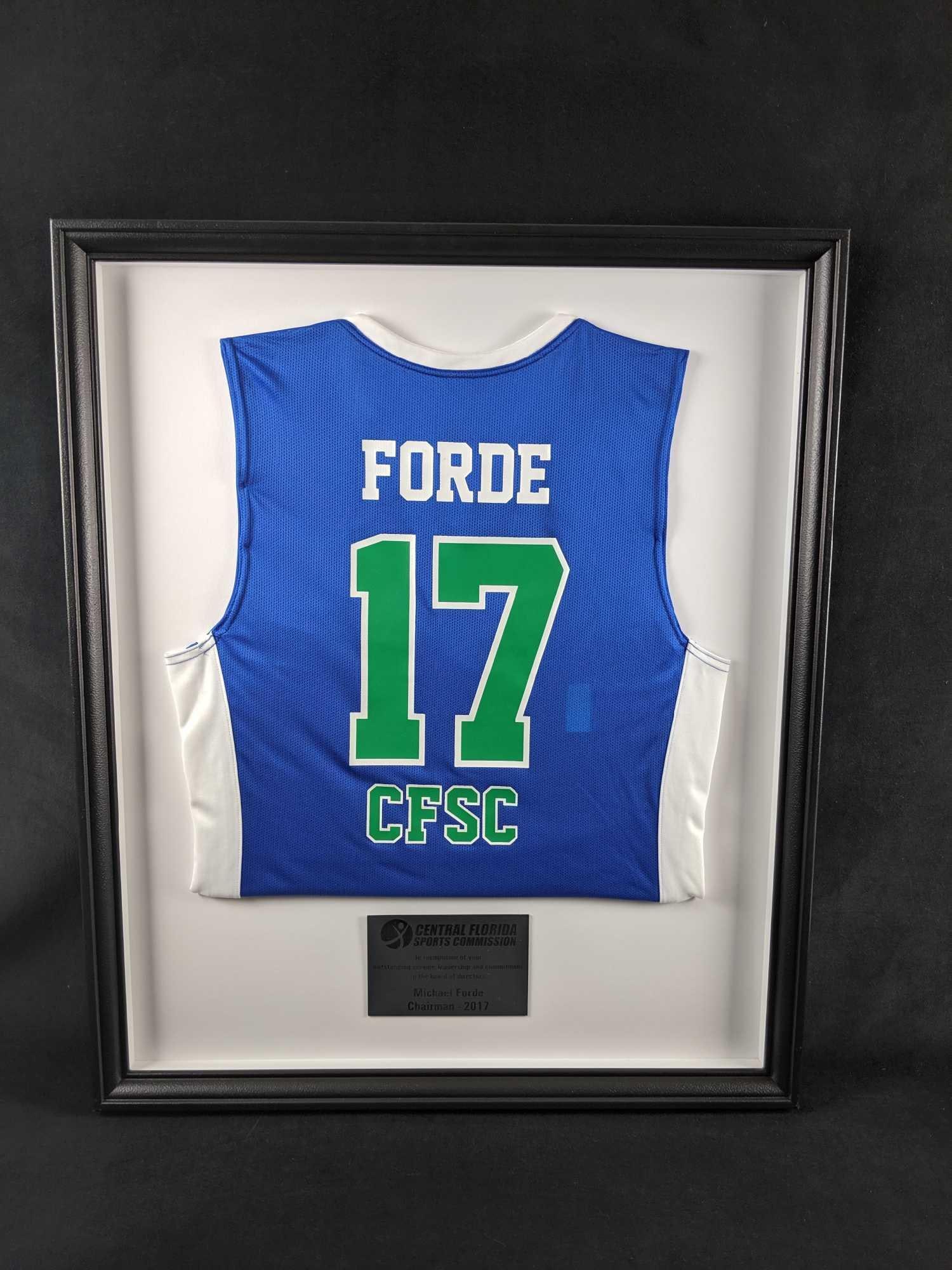 Framed Central Florida Sports Commission Service Award Jersey 2017: Special framed jersey originally given to Orlando Magic head of sales, Michael Forde in 2017. Shadowbox is approx 26" x 2" x 31". Frame is in good, used condition with only a few minor chips