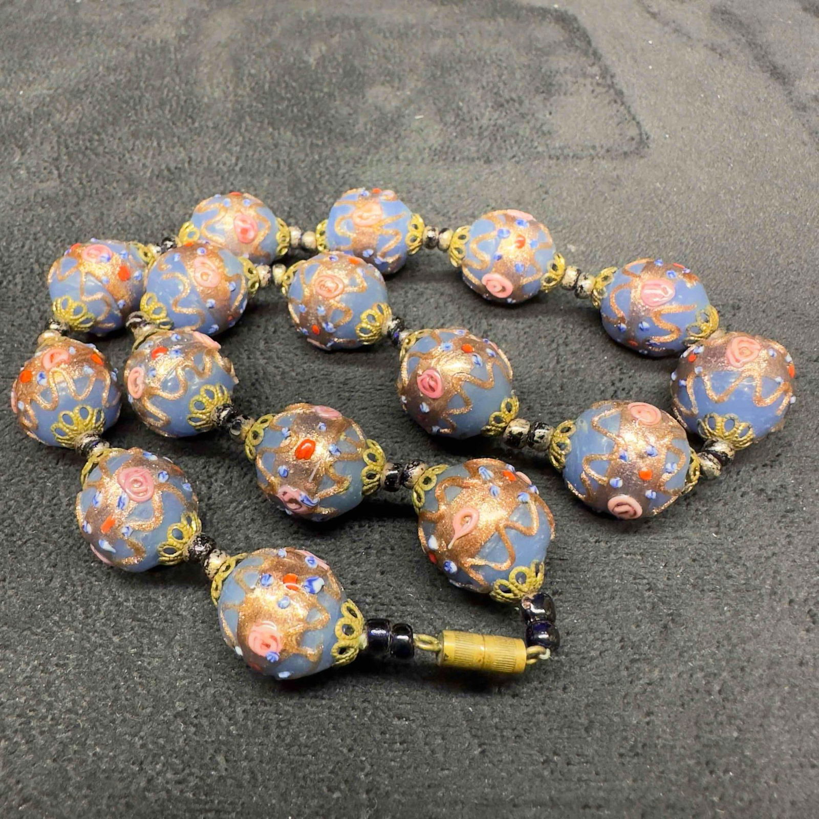 Venetian Murano Glass Lamp Work Fiorato Blue Bead Floral Beaded Necklace A100: Venetian Murano Glass Lamp Work Fiorato Blue Bead Floral Beaded Necklace A100. Necklace with blue glass beads with beautiful floral designs on each. The necklace features copper colored accents. The n