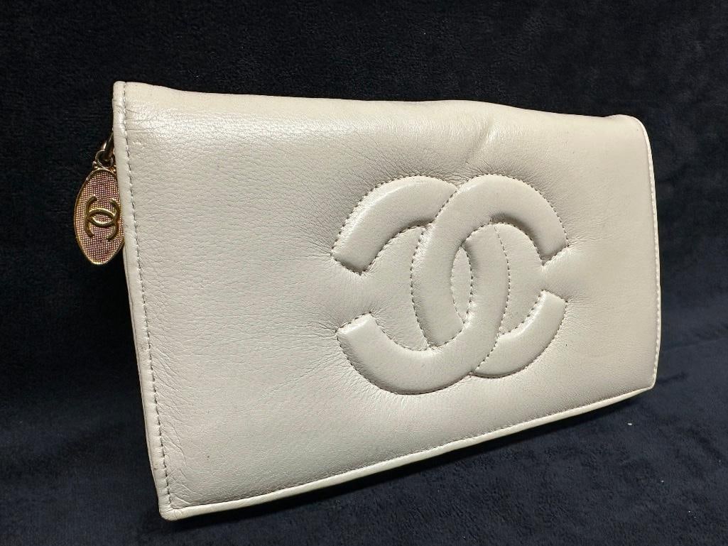 Vintage Chanel White Leather Wallet Clutch: Chanel white leather wallet clutch featuring the iconic embossed interlocking CC logo, snap closures, gold-tone hardware, and interior card slots and zippered pouch. Made in France and marked