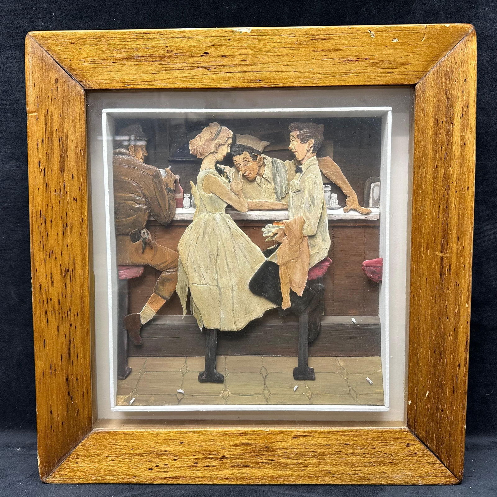 Vintage 3D Relief Wall Art Diner Counter Scene in Wooden Shadowbox Frame: Vintage 3D relief artwork showing a classic diner counter scene with four figures. Textured, layered design set inside a deep wooden shadowbox-style frame. The frame shows age-related wear. Unknown ar