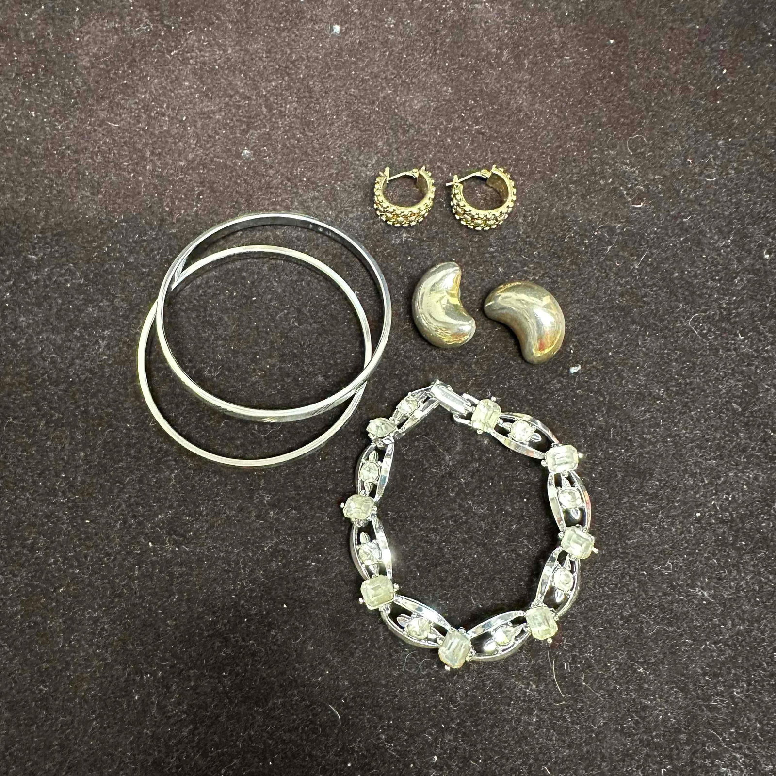 Monet Costume Jewelry Lot Bracelet Bangles Earrings K26: Group of signed Monet costume jewelry including a silver tone rhinestone link bracelet with emerald cut and round stones, a pair of etched silver tone bangles, gold tone hoop earrings with textured be