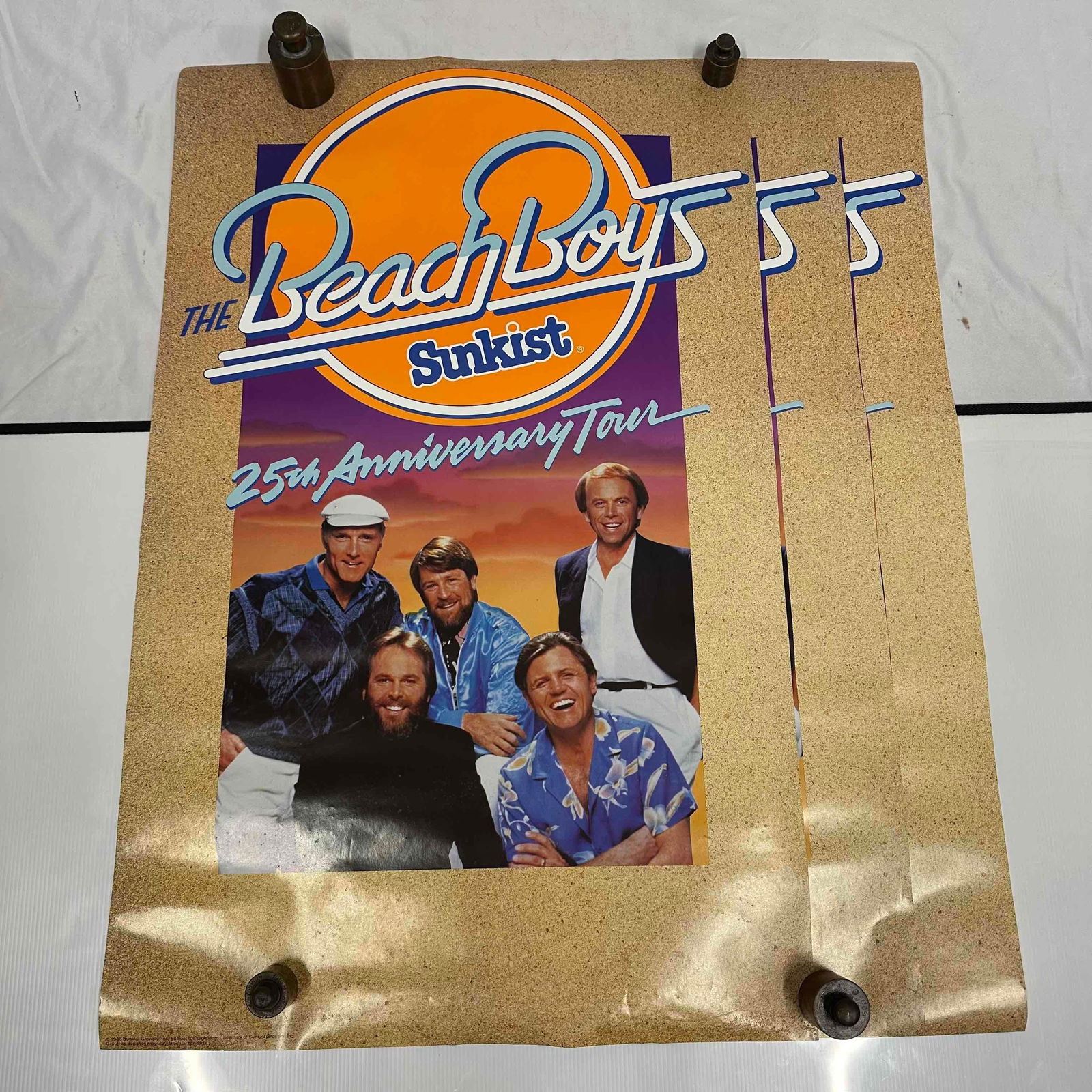 Sunkist 25th Anniversary Tour The Beach Boys Poster1986 Original Set of Three: Original The Beach Boys 25th Anniversary Tour poster sponsored by Sunkist. Features vibrant graphics with the band’s logo above a group portrait of members against a purple and orange background. Vi