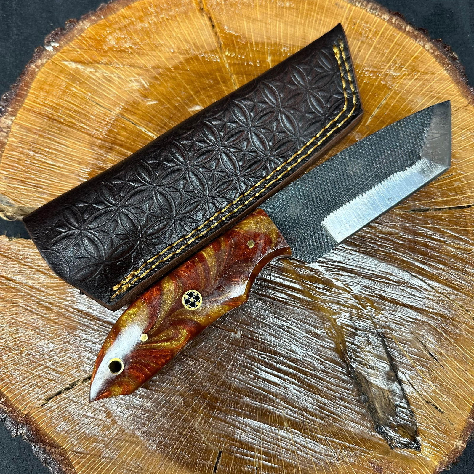 Brown Orange Colorway Handle MHS Cutlery Knife Cleaver Style Blade Q5: Fixed small, cleaver-style blade knife by MHS Cutlery featuring a textured steel straight back blade and decorative spine work. The handle features a contoured brown and orange colorway, wood/epoxy re