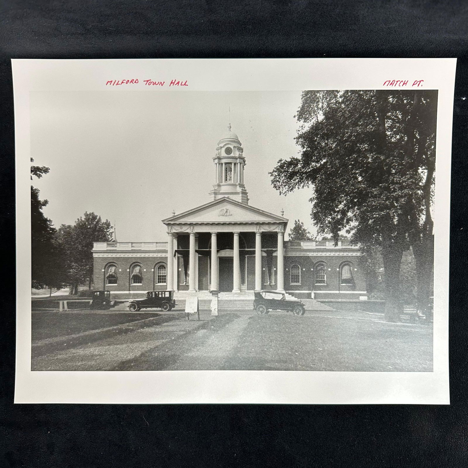 Milford Town Hall Analog Photography Print Black and White: Black and white analog photography print depicting Milford Town Hall, a classic American civic building with neoclassical columns and a clock tower. Vintage automobiles are visible in front of the str