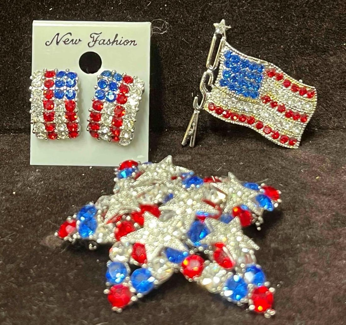 New Fashion Red White And Blue American Flag Earrings & Brooches Set: This lot contains a New Fashion Red White And Blue American Flag Earrings & Brooches Set. The set fits in a small 3 1/4" x 2 1/4" x 1 1/4" box. Total weight is 1oz. Overall the America Jewelry set is