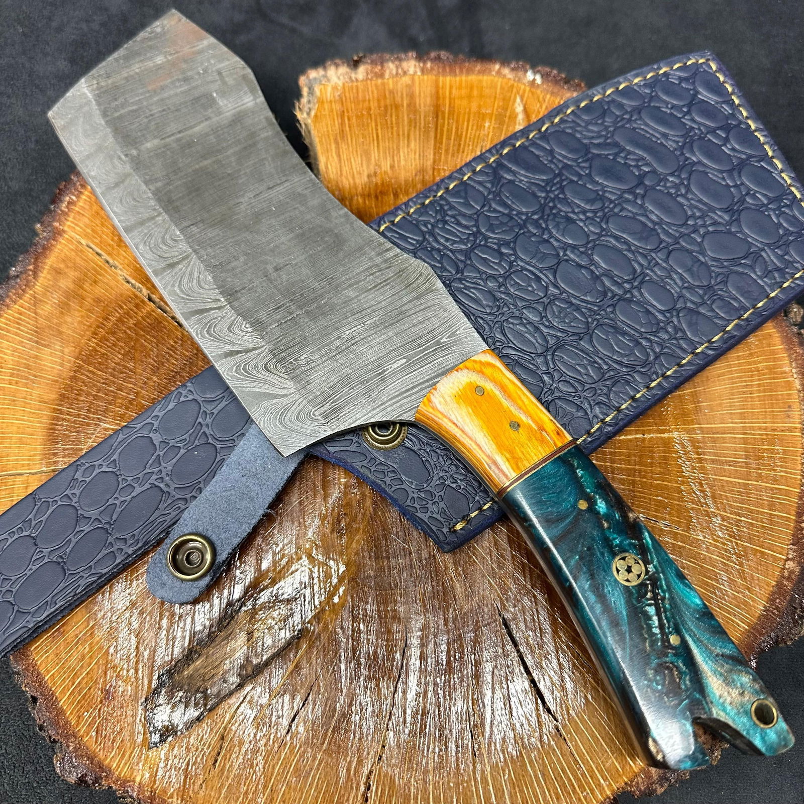 Large MHS Cutlery Cleaver Knife with Textured Blade Black Aqua Blue Handle Q33: A large MHS Cutlery fixed-blade cleaver knife featuring a textured steel blade and a multi-colored handle with layered wood and epoxy resin style accents. Includes fitted blue leather sheath with embo
