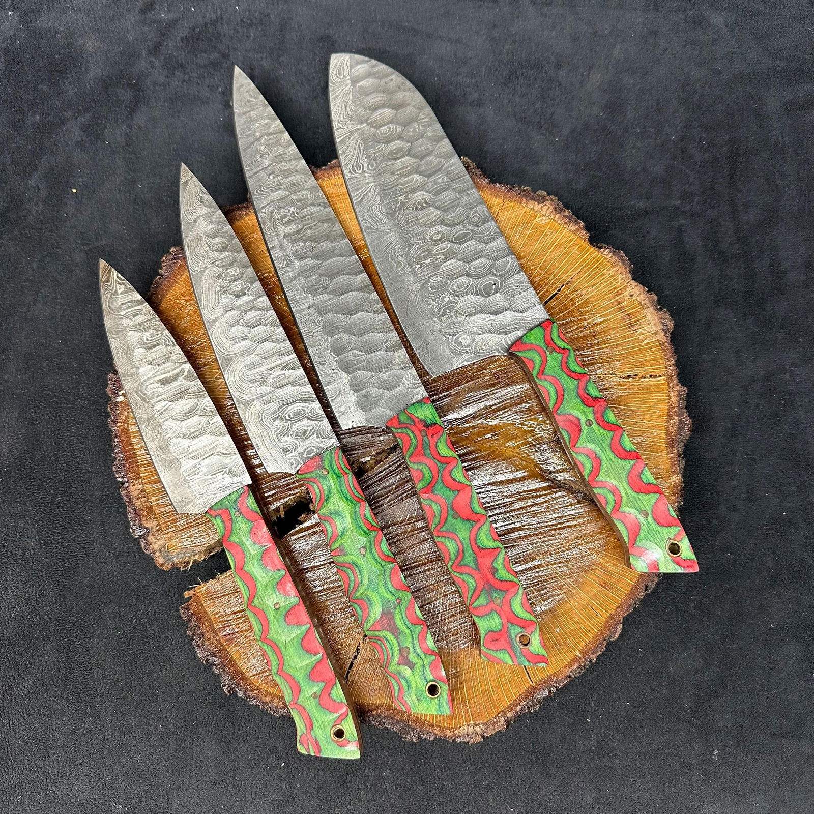 MHS Cutlery Steel Chef Knife Set 4 Knives Wood Red Green Swirl Handles: Set of four MHS Cutlery steel chef knives. Each knife features a patterned style blade with full tang construction, mixed wood/epoxy resin handles, and brass pins with lanyard holes. Blades show visib