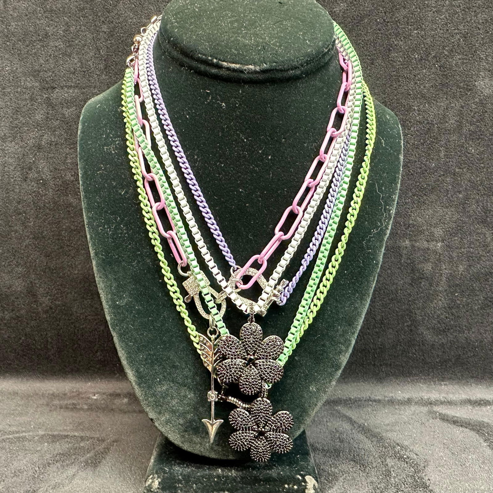 Melania Clara Assorted Multi Colored Necklace Flower Arrow Accent Chain Set M3: The Melania Clara necklace set features a magnet clasp closure. The necklaces have magnet extender clasp closures. Each necklace showcases modernist designs with gold-toned and rhinestone accents. The