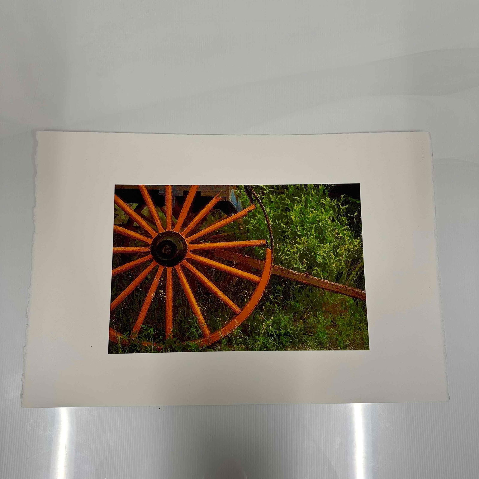 Rustic Wagon Wheel Fine Art Print on Arches France Deckle-Edge Paper: Fine art print of a rustic wagon wheel set against green foliage. Printed on high-quality Arches France watercolor paper, deckle-edged, known for its durability and artist-grade texture. Light handlin