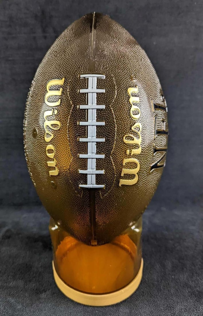 Snack Factory Plastic NFL Wilson Football Bank: Snack Factory Plastic NFL Wilson Football Bank. This is approx 6" x 6" x 13" and it weighs 0.44lb. The bank is in a good, used condition with some wear and scuffs. There is some sticker residue on the