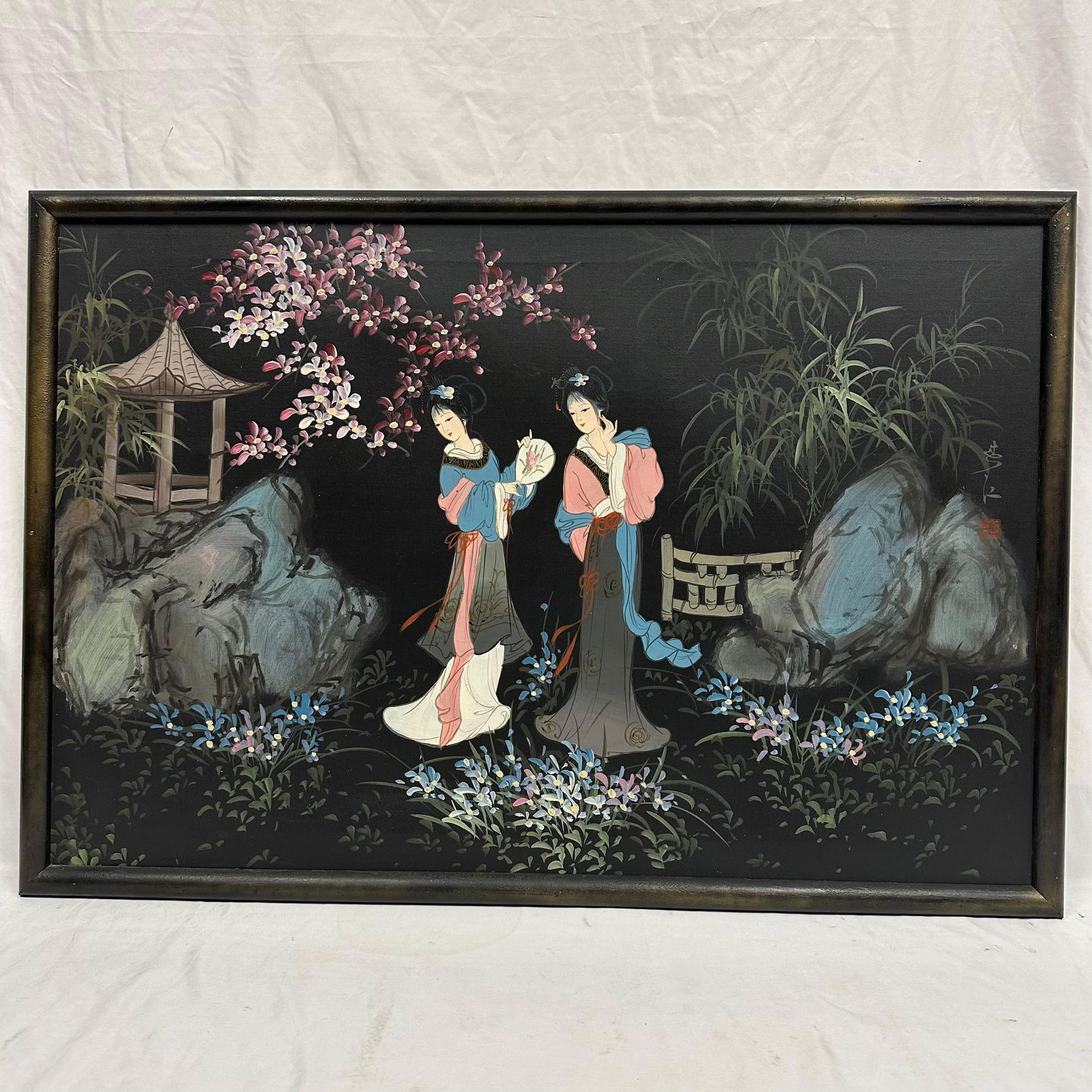 Asian Geisha Women in a Garden Under Cherry Blossoms Framed Oil on Canvas: Asian painting featuring two elegant geisha women in traditional dress, strolling beneath blooming cherry blossoms amid a tranquil garden with rocks, bamboo, and a small pagoda. The artwork is artist-