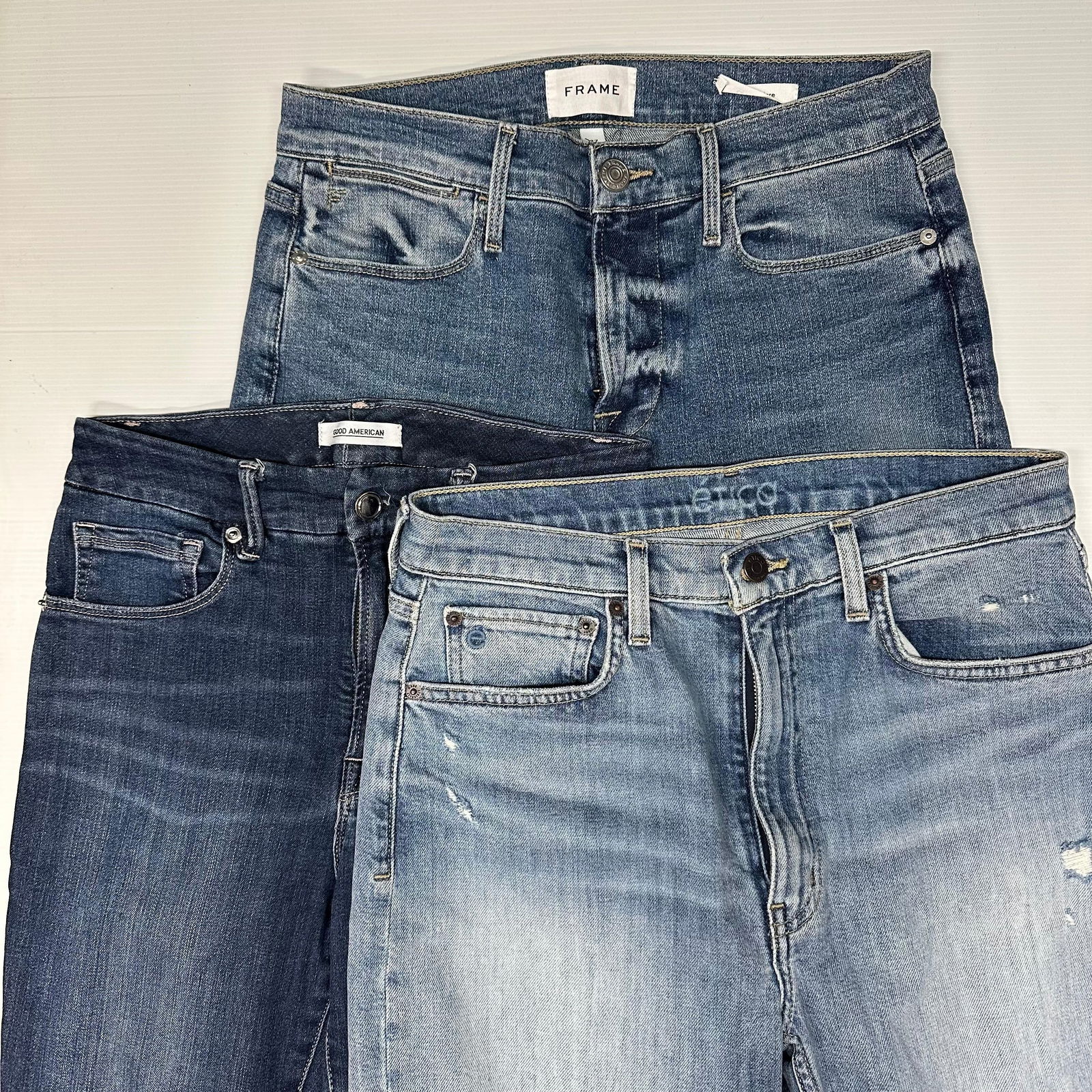 Three Women Denim Jeans Lot Etica Frame Good American Brands: The lot includes three pairs of women’s denim jeans. Each pair is a medium blue wash with light fading and distressed details. Five-pocket construction with button and zip fly. Etica, Good American,