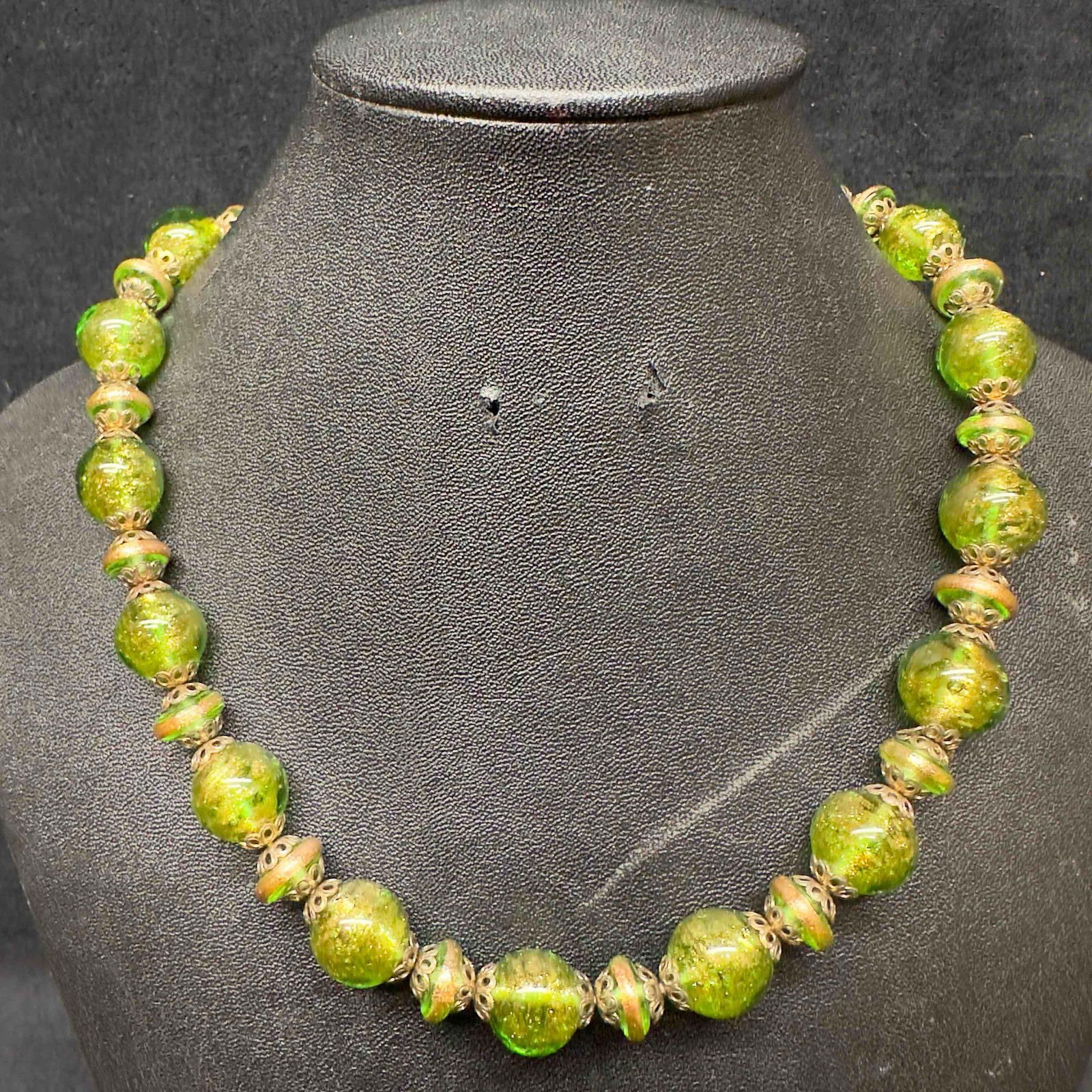 Venetian Murano Art Glass Lamp Work Green Bead Copper Accents Beaded Necklace C97: Venetian Murano Art Glass Lamp Work Green Bead Copper Accents Beaded Necklace C97. Necklace with green colored glass beads with beautiful designs on each. The necklace features copper accents. The nec