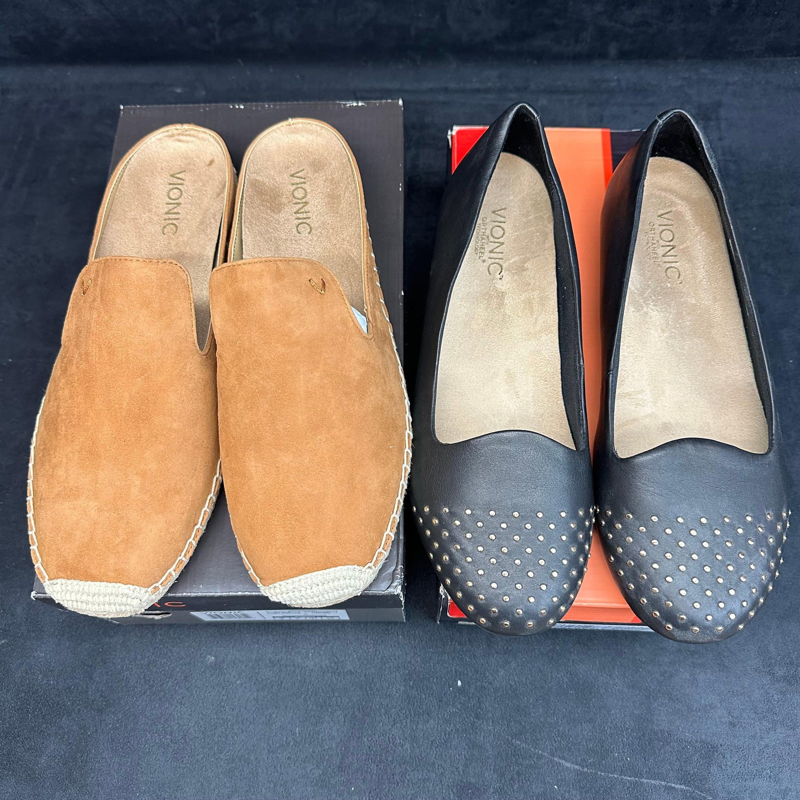 Vionic Women’s Shoe Lot Tan Suede Slip-On Mules and Black Studded Flats 2 Pairs: Pair of Vionic brand women’s shoes, both featuring the brand’s signature Orthaheel comfort technology. The lot includes: Tan Suede Slip-On (Style: Coast Santorini, Size 9) – New in box with pac