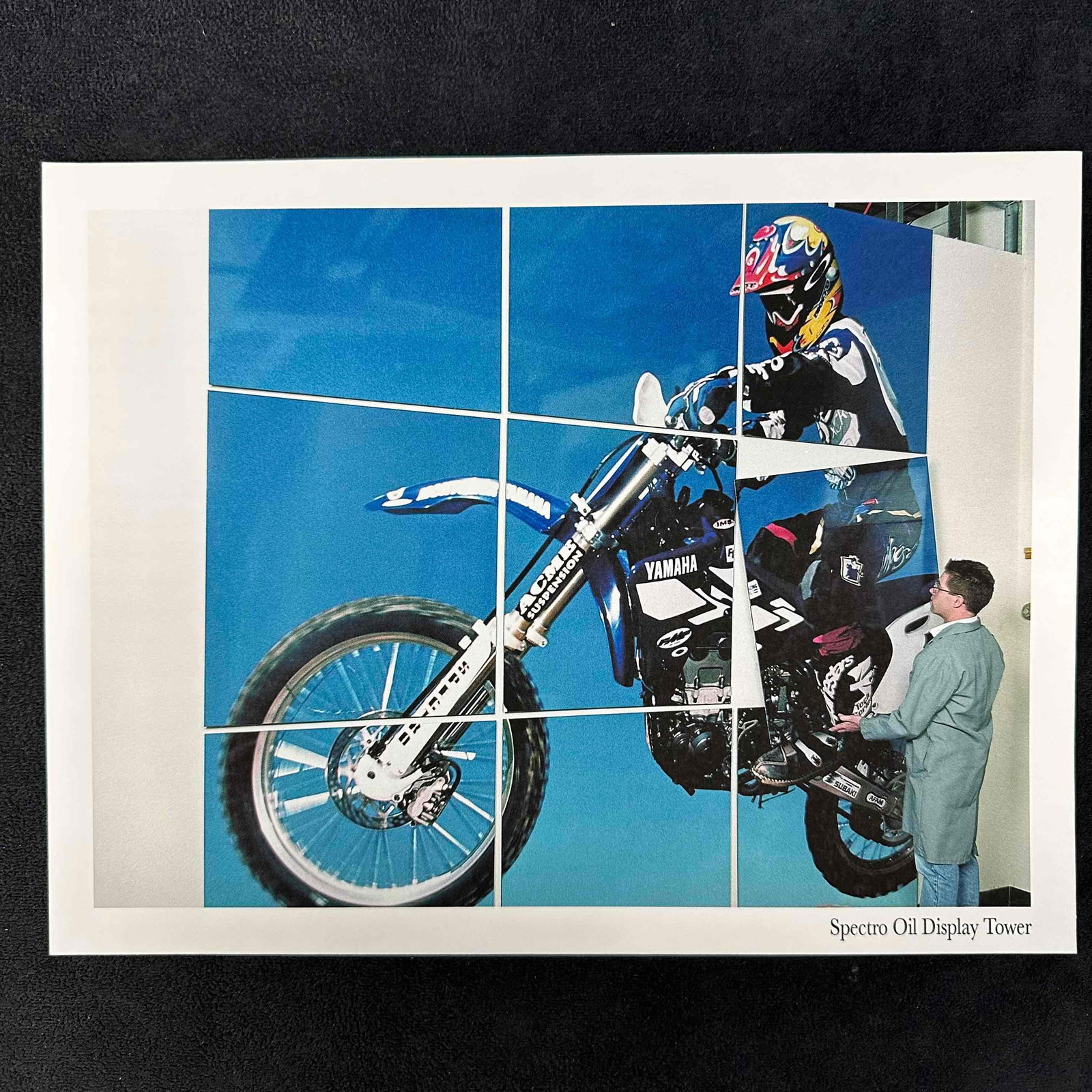 Spectro Oil Display Tower Color Photo Print: Vibrant color photo print depicting a large Yamaha motocross display installation, assembled as a multi-panel tower mural. The image features a rider mid-action on a blue Yamaha dirt bike, with a work