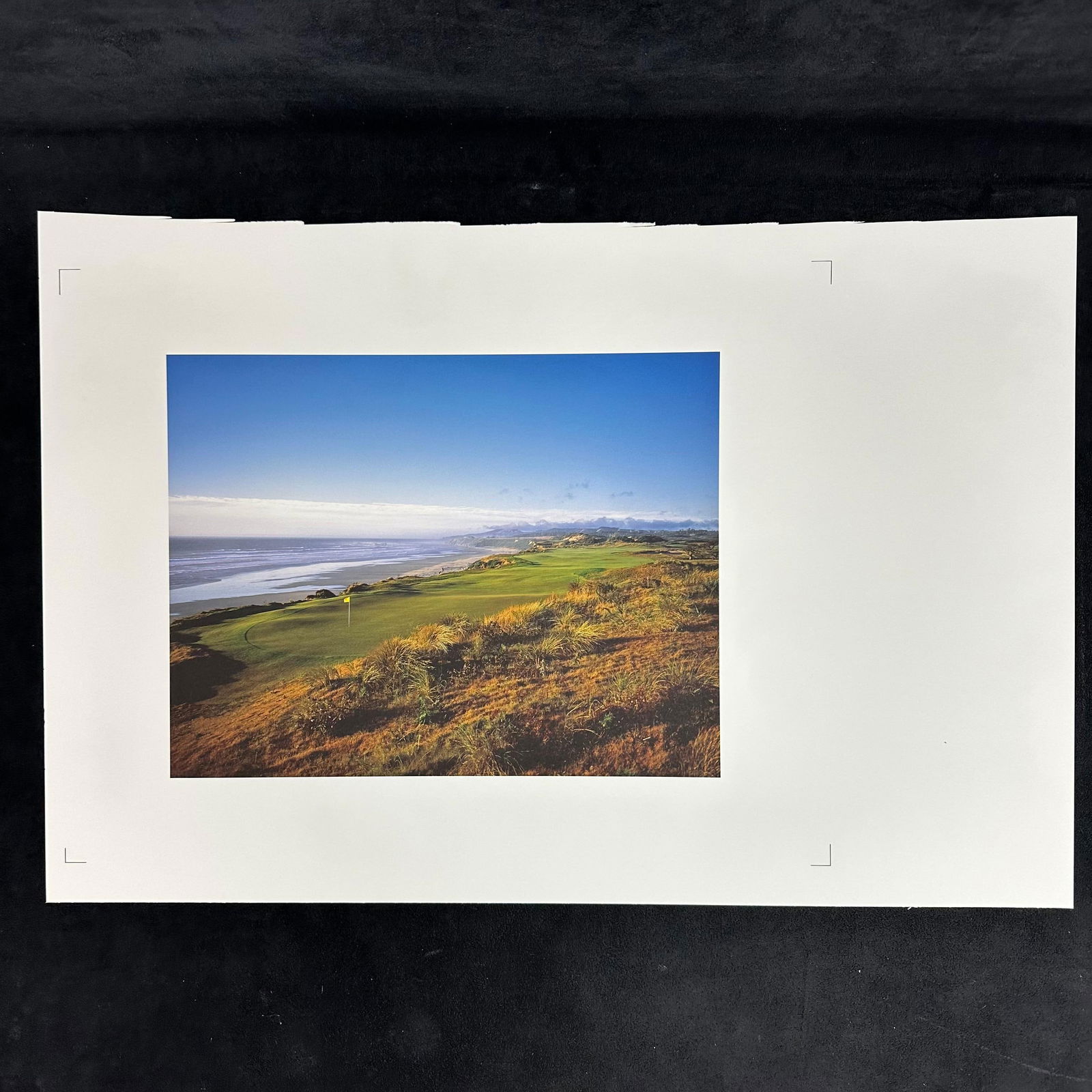 Bandon Dunes Golf Course Coastal Landscape Oregon Coast Photography Print Offset: Color photograph print capturing the scenic Bandon Dunes Golf Course along the Oregon coastline. The image highlights the green fairway overlooking the Pacific Ocean with distant mountains under a cle