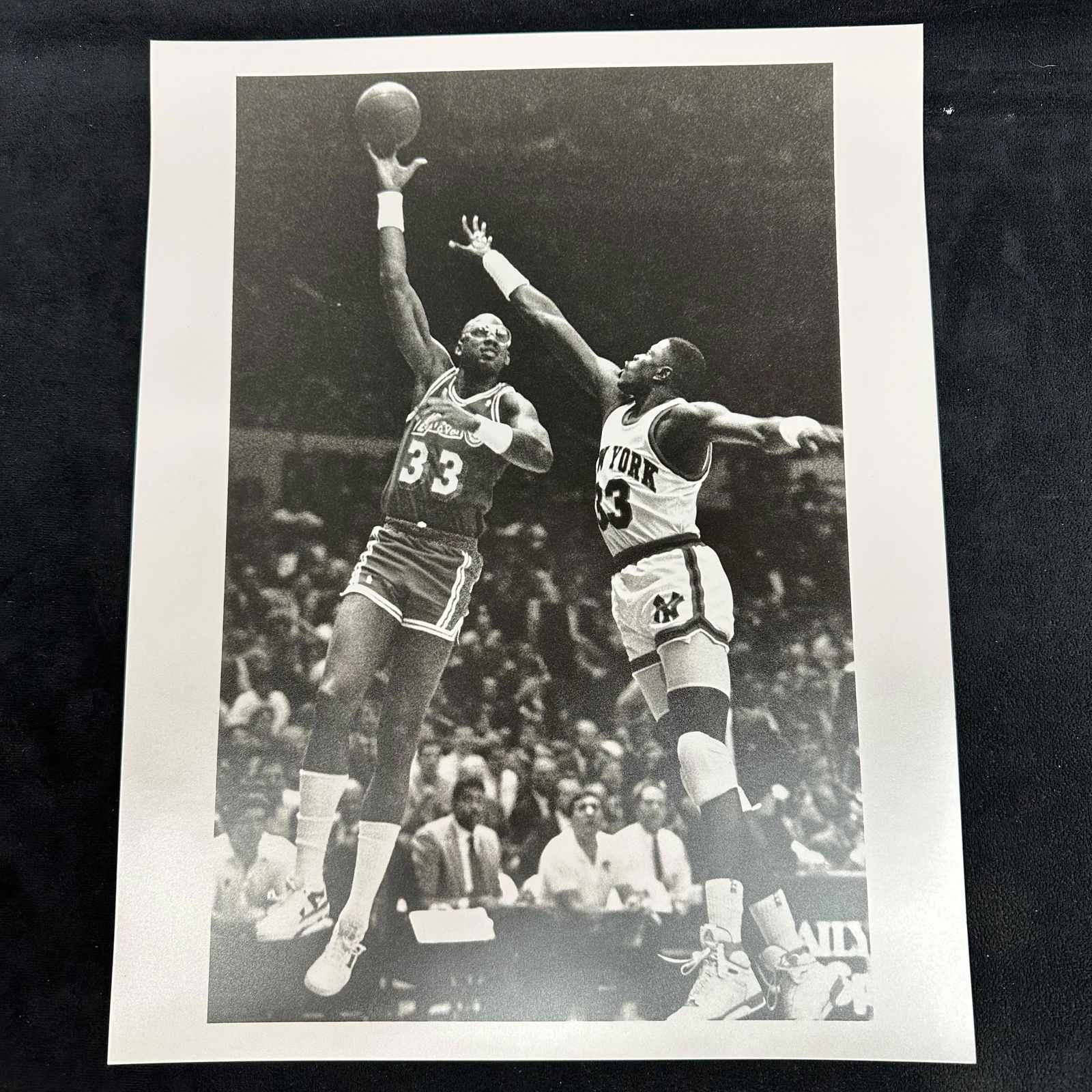 Analog Black and White Basketball Photo Print Kareem Abdul-Jabbar vs. Patrick Ewing Skyhook Shot: Vintage black and white analog photo print capturing Kareem Abdul-Jabbar (#33, Los Angeles Lakers) performing his iconic skyhook shot against New York Knicks Patrick Ewing #33. Printed on pearl resin-