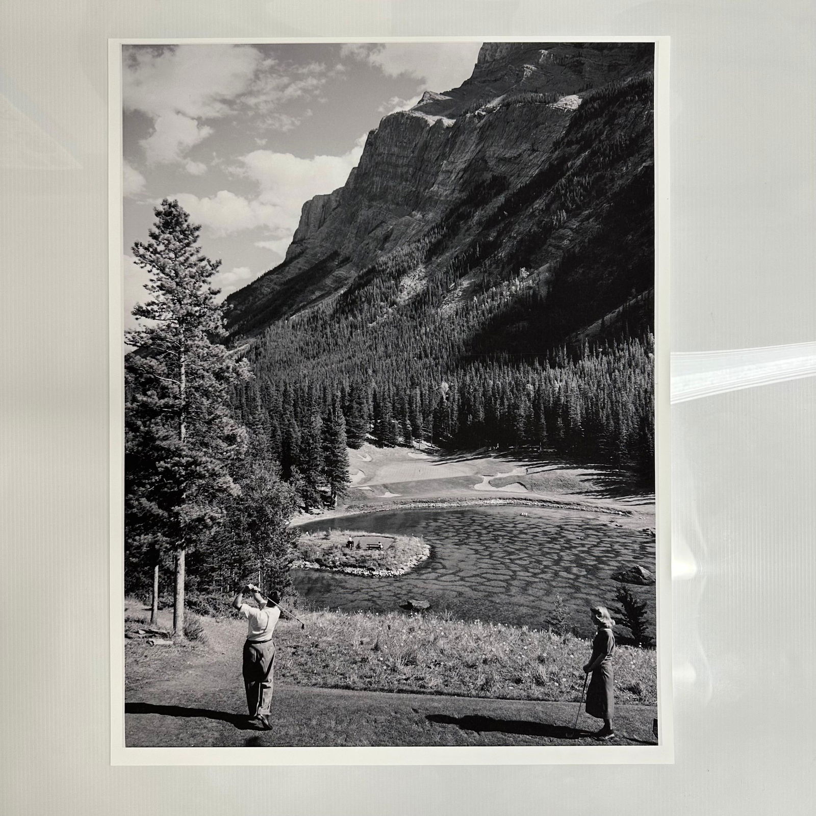 Banff Springs Golf Landscape Fine Art Photograph Print Devil's Cauldron 4th Hole: Black-and-white photograph print, of a vintage golf landscape of Banff Springs, depicting golfers on a mountain course with a dramatic forested landscape and towering cliffs in the background. Printed