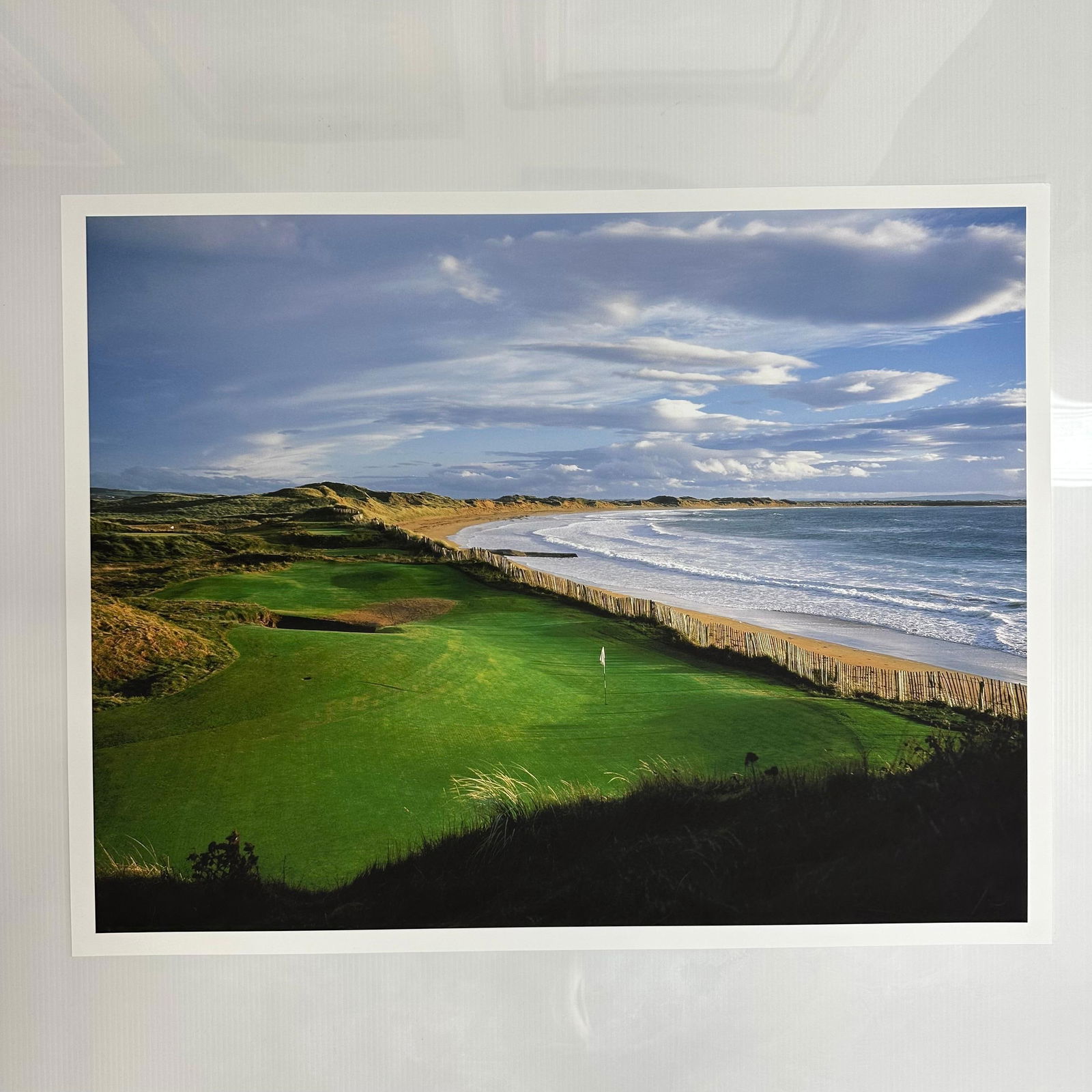 Coastal Sweeping Ocean Golf Course Landscape Photograph Print Oceanfront Fairway Thin Border: Color photograph print capturing a sweeping coastal golf course view, with the fairway running parallel to the ocean and framed by rolling dunes under a dynamic cloud-filled sky. Printed on high-quali