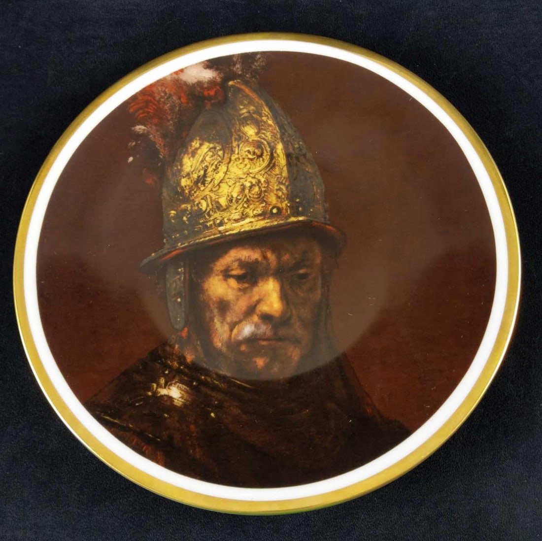 Heinrich Collectable Plate Man W The Gold Helmet: "The Man with the golden helmet" is a portrait from the circle of the Dutch painter Rembrandt van Rijn, long thought to be an original Rembrandt. In the 1970s, it turned out that that the portrai