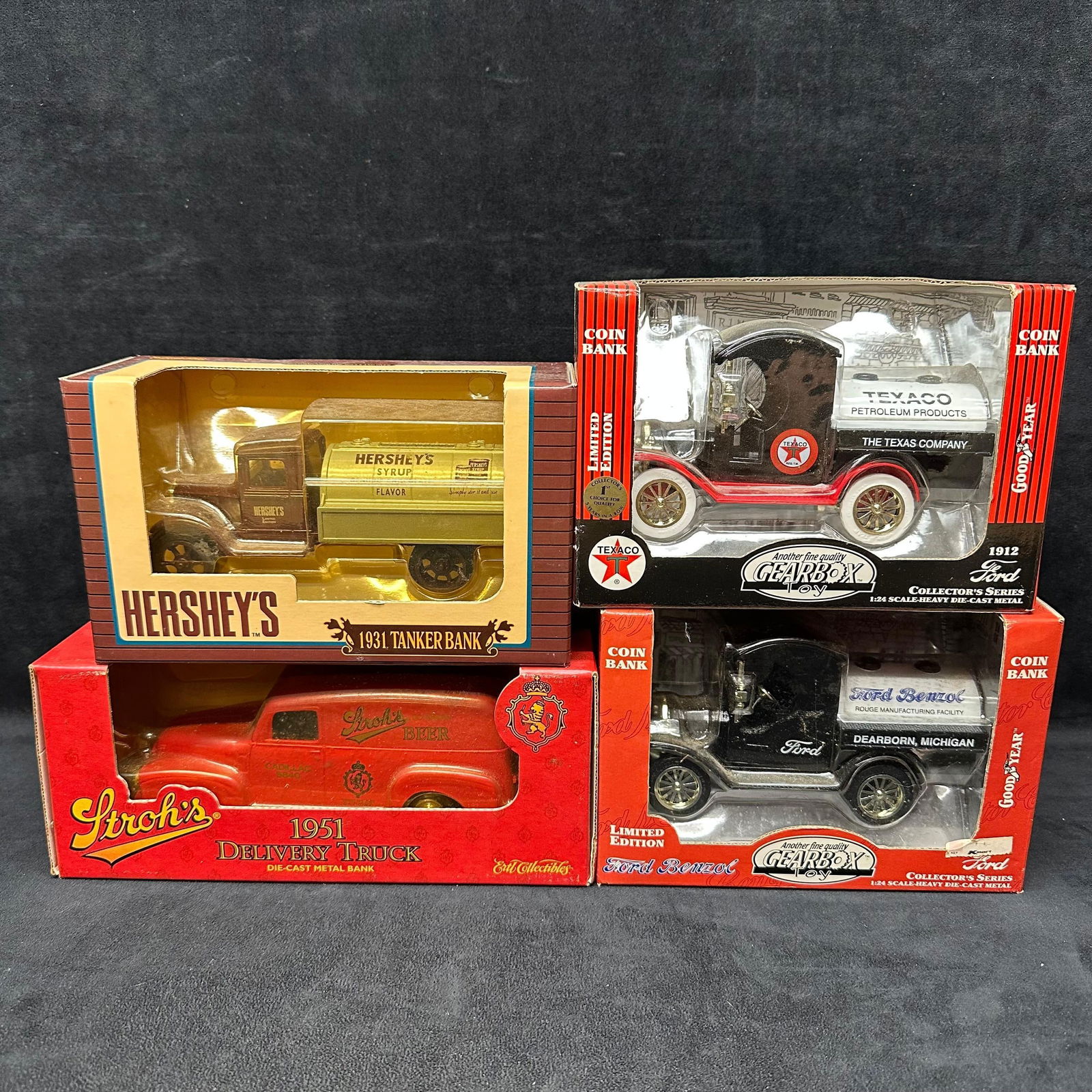 Die-Cast Coin Banks and Trucks Hershey Stroh Texaco Ford 1:24 Scale: Set of four collectible die-cast metal coin banks and trucks, each presented in original boxes. Includes a Hershey’s 1931 Tanker Bank, Stroh’s 1951 Delivery Truck, Texaco 1912 Ford Tanker, and For
