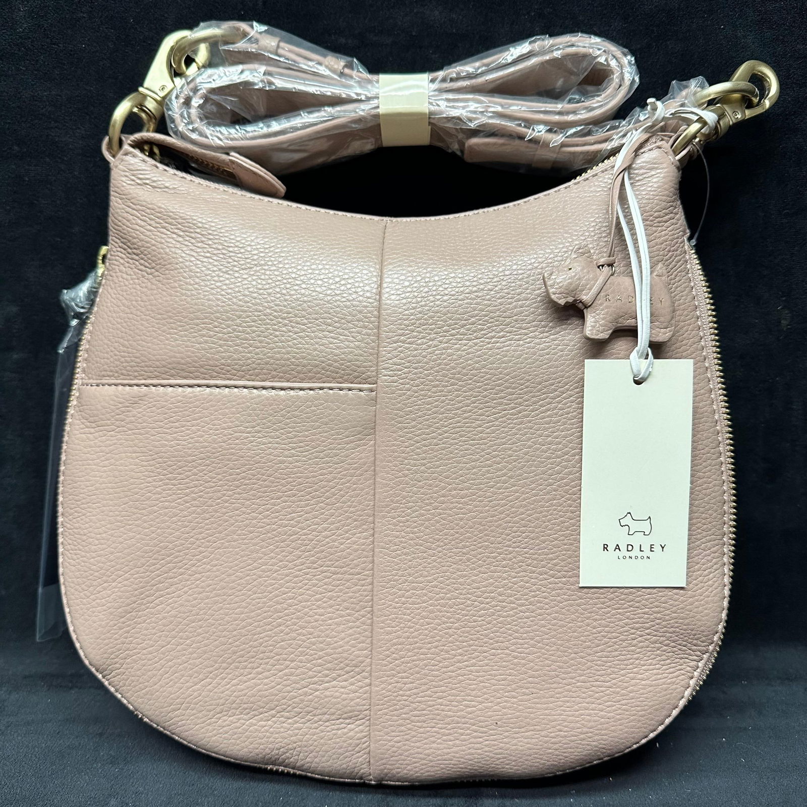 Radley London Blush Pinkish Taupe Pebbled Leather Crossbody Bag: Radley London crossbody bag crafted in blush-toned pebbled leather. Features gold-tone hardware, top zip closure, and adjustable detachable shoulder strap. Exterior includes subtle Radley London