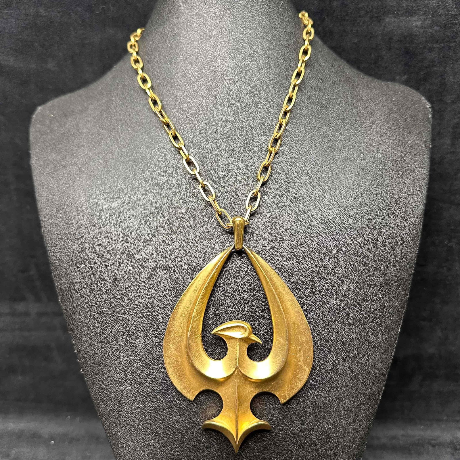 Crown Trifari Gold Tone Eagle Pendant Vintage Necklace: Striking vintage Crown Trifari necklace featuring a large stylized eagle pendant in a textured matte and polished gold-tone finish. The bold mid-century modern design showcases Trifari’s craftsmansh