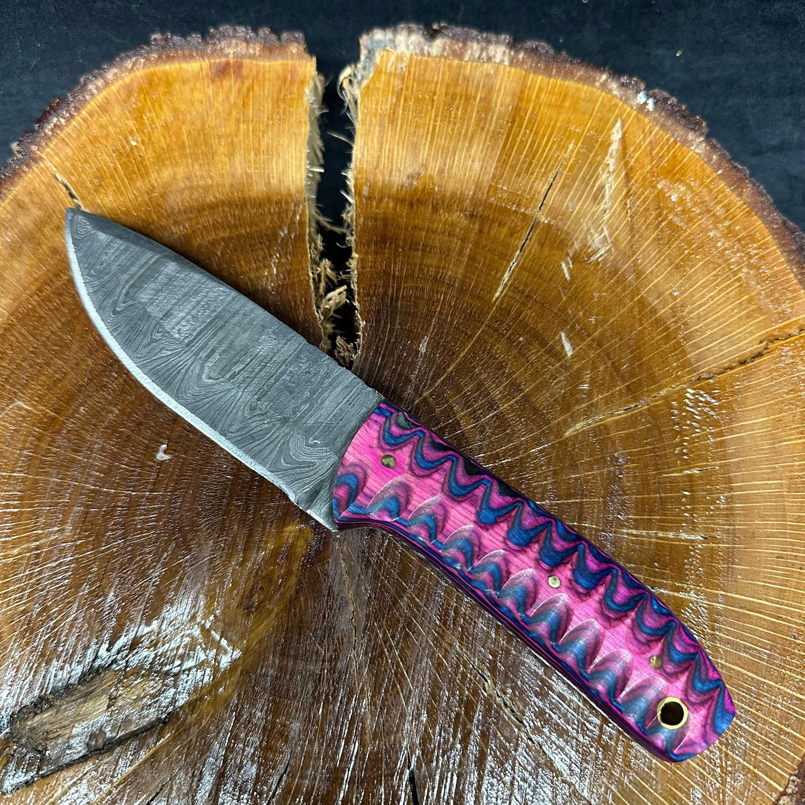 MHS Cutlery Fixed Patterned Steel Blade Knife P37 Purple Pink Blue: Fixed blade knife by MHS Cutlery featuring a patterned steel blade with a curved profile. The handle is constructed with multi-tone stabilized material in blue, pink, and purple hues, accented with mo