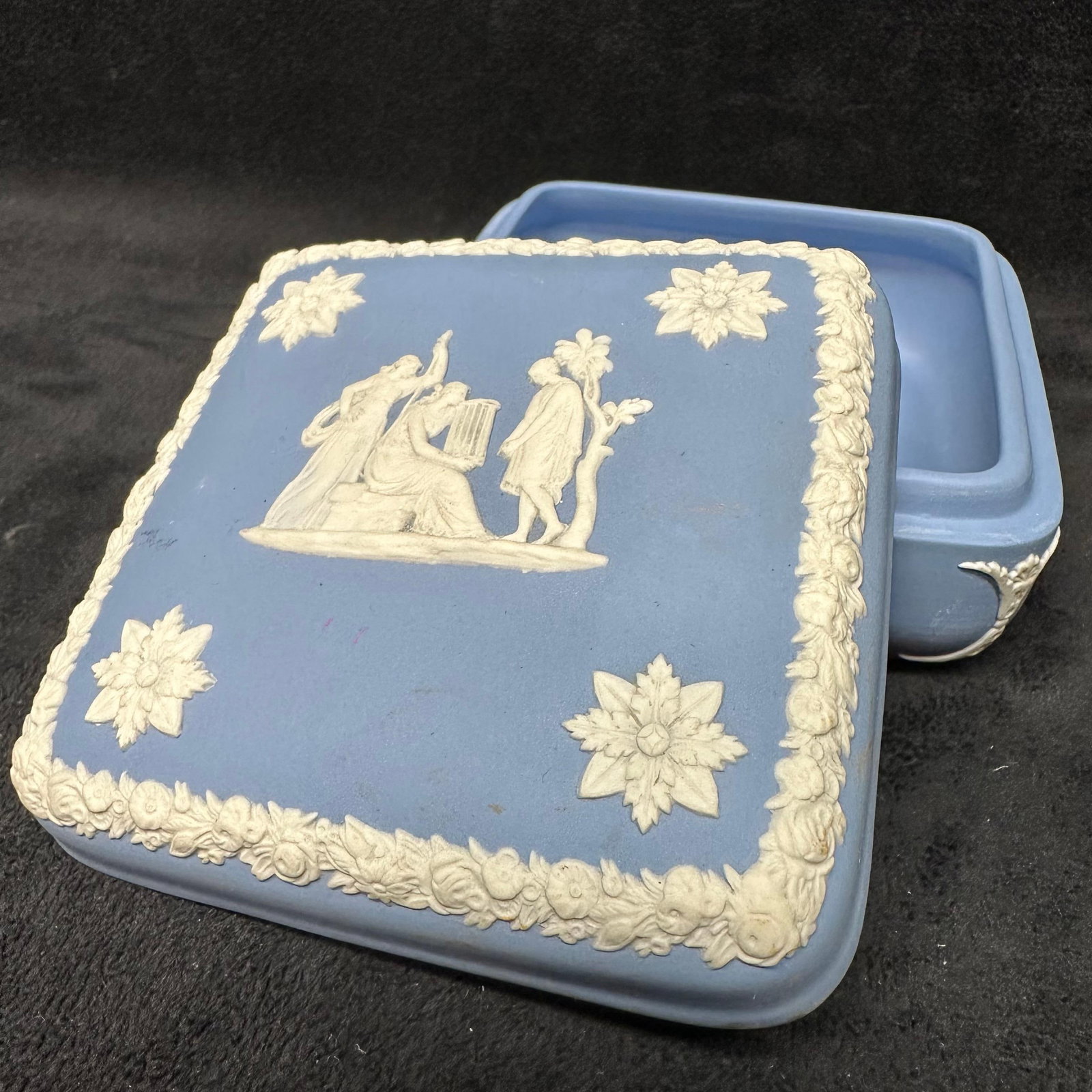 Wedgwood Blue Jasperware Trinket Jewelry Box Square Floral Borders: A blue matte finish square-shaped trinket box, Wedgwood, and their classic piece of pottery Jasperware range. Engraved on the bottom is Made in England, Wedgwood. The piece is a blue and white colorin