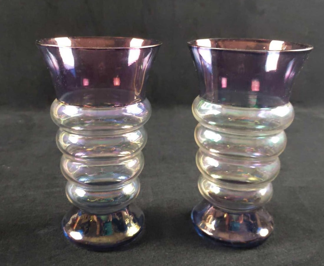 Vintage Art Deco Drinking Glasses Lot Of Two: Two vintage drinking glasses with a metallic type finish on the tops and bottoms, which change colors depending on you light. Each also has a spiral in the middle. Maker or date is unknown. Glas